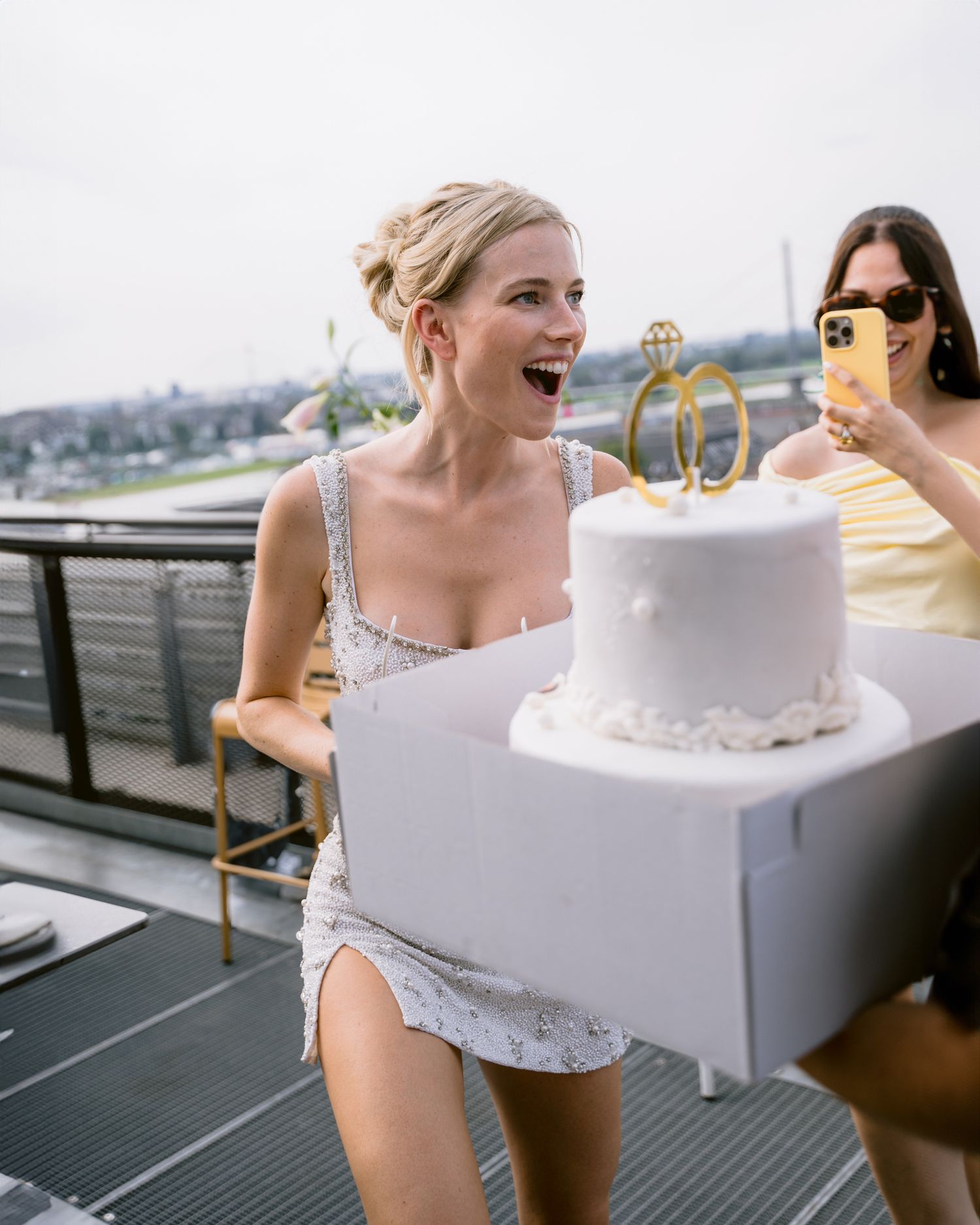 Bride photography europe candid and editorialA white wedding cake sits on a table at an outdoor reception venue with guests gathered around.
