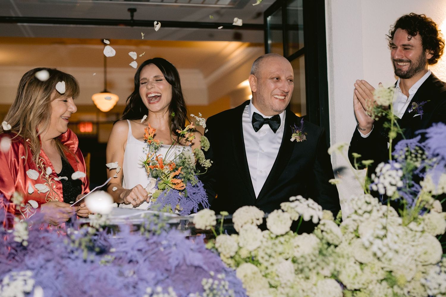 Wedding guests sharing laughter and joy at an elegant reception with floral decorations.