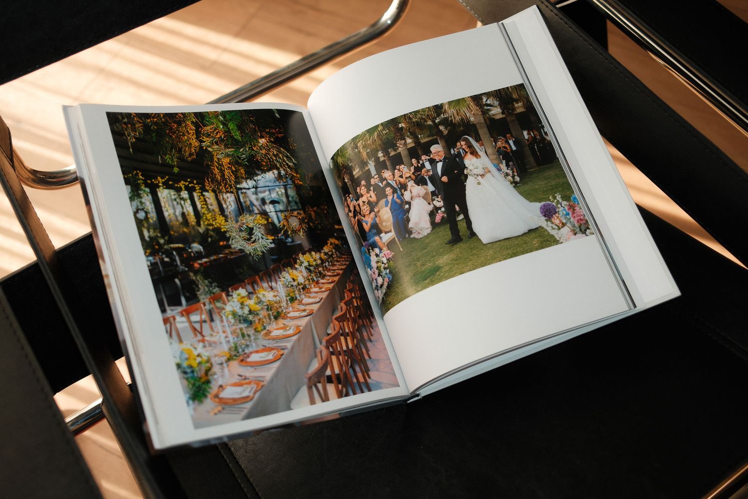 Someone flips through pages of a wedding photo album showing outdoor reception table settings and celebration moments.