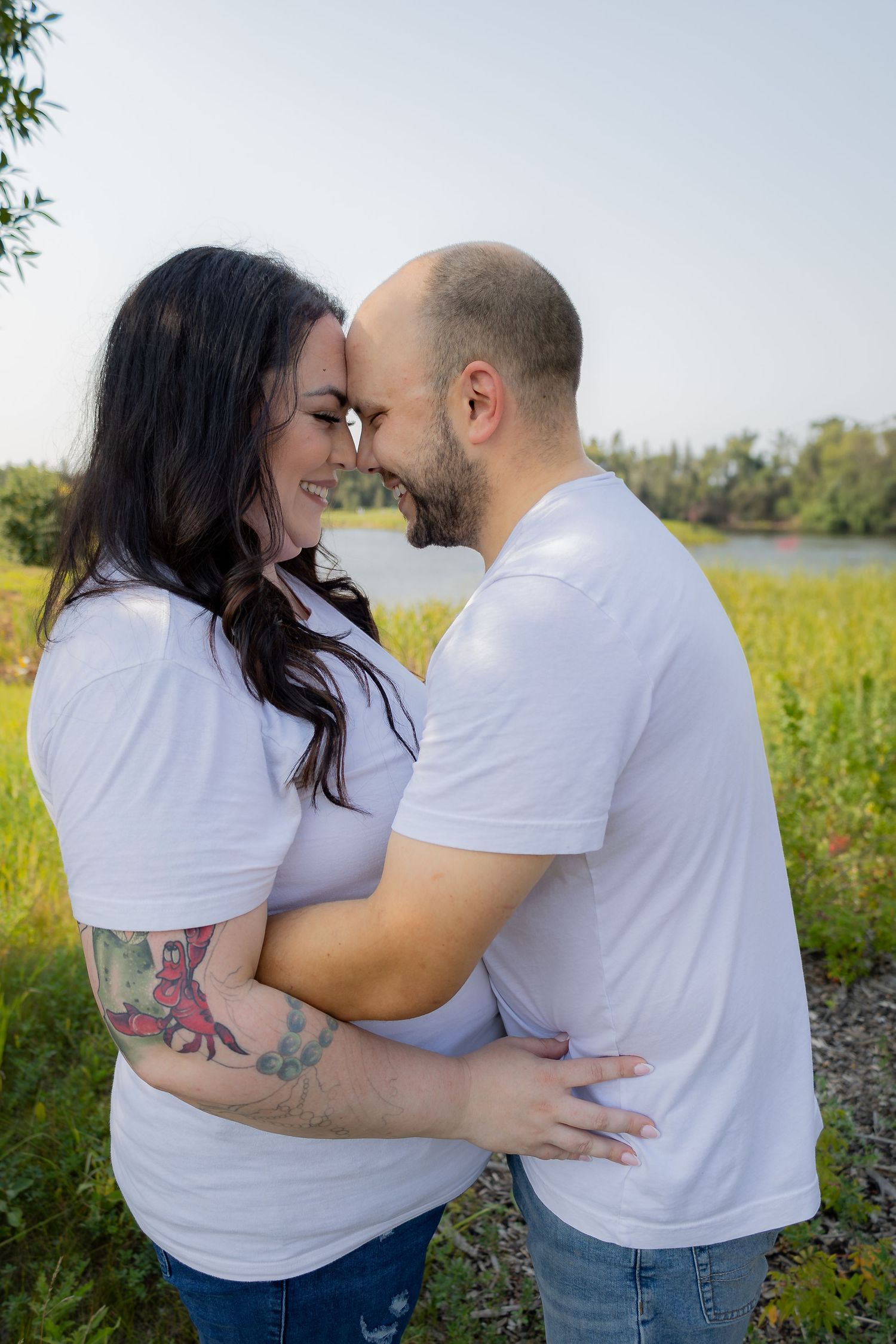 Couple in matching white shirts share intimate moment during outdoor photo session.