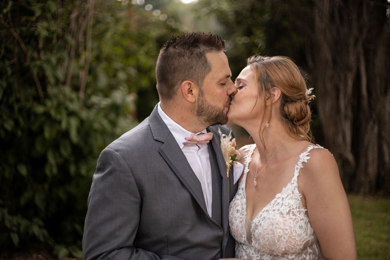 An intimate wedding portrait captured among trees with soft natural lighting.