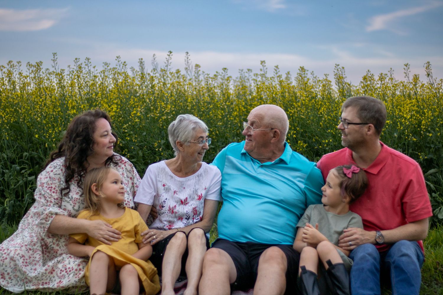Extended family sitting together in blooming canola field.