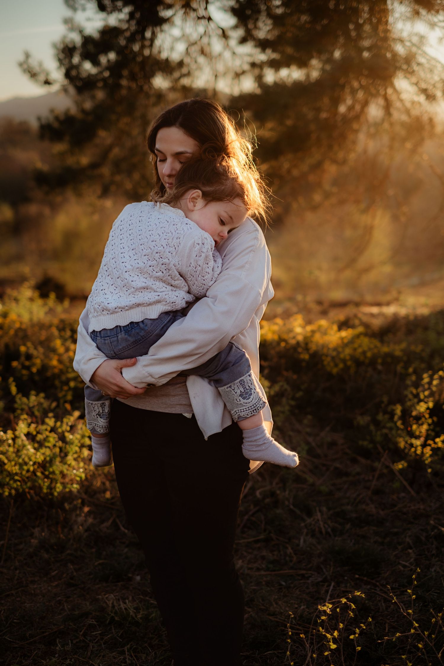 candid family cuddles under a tree in a golden hour family session near Pulborough