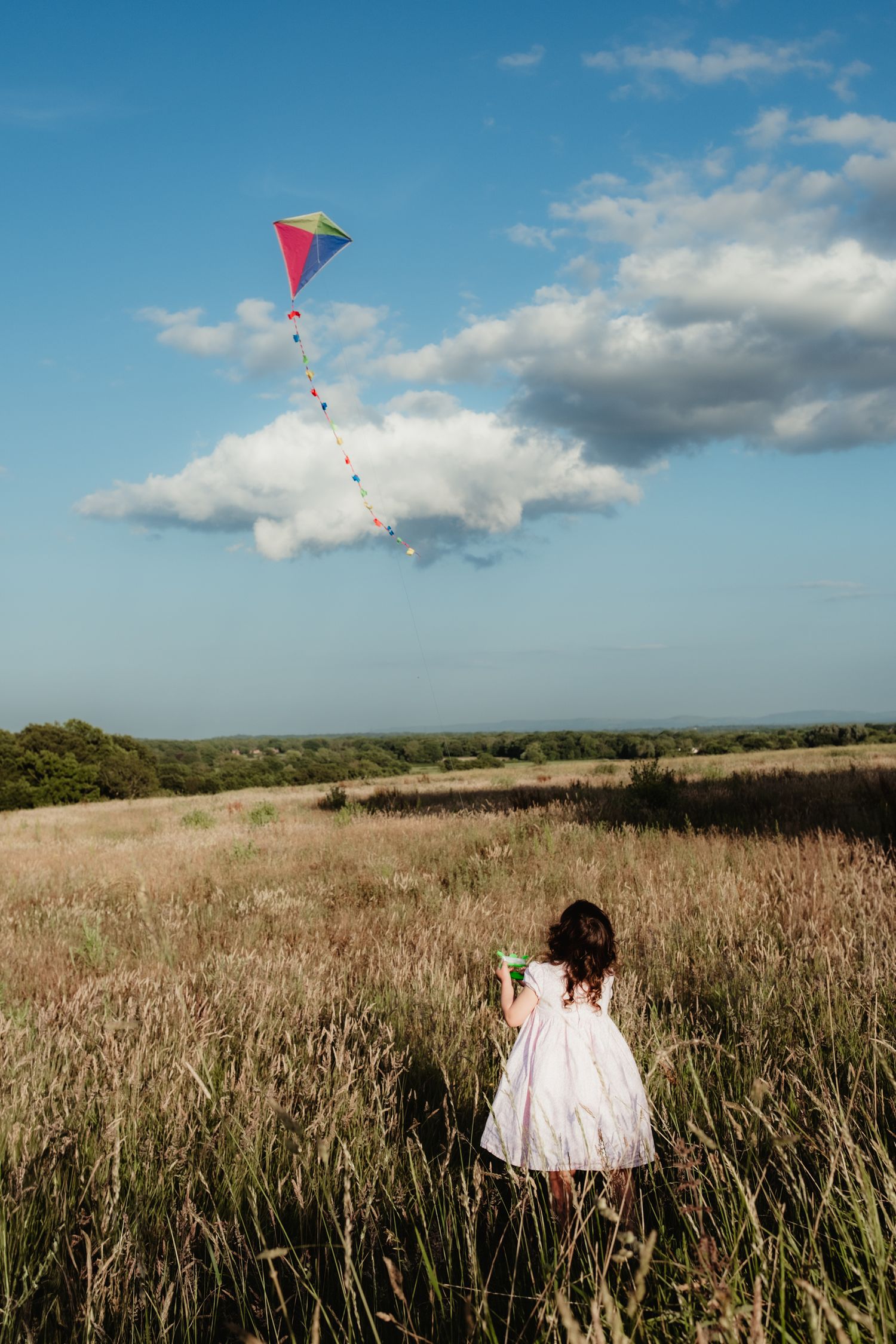 young girl flying a kite during an outdoor lifestyle family photography session near Horsham