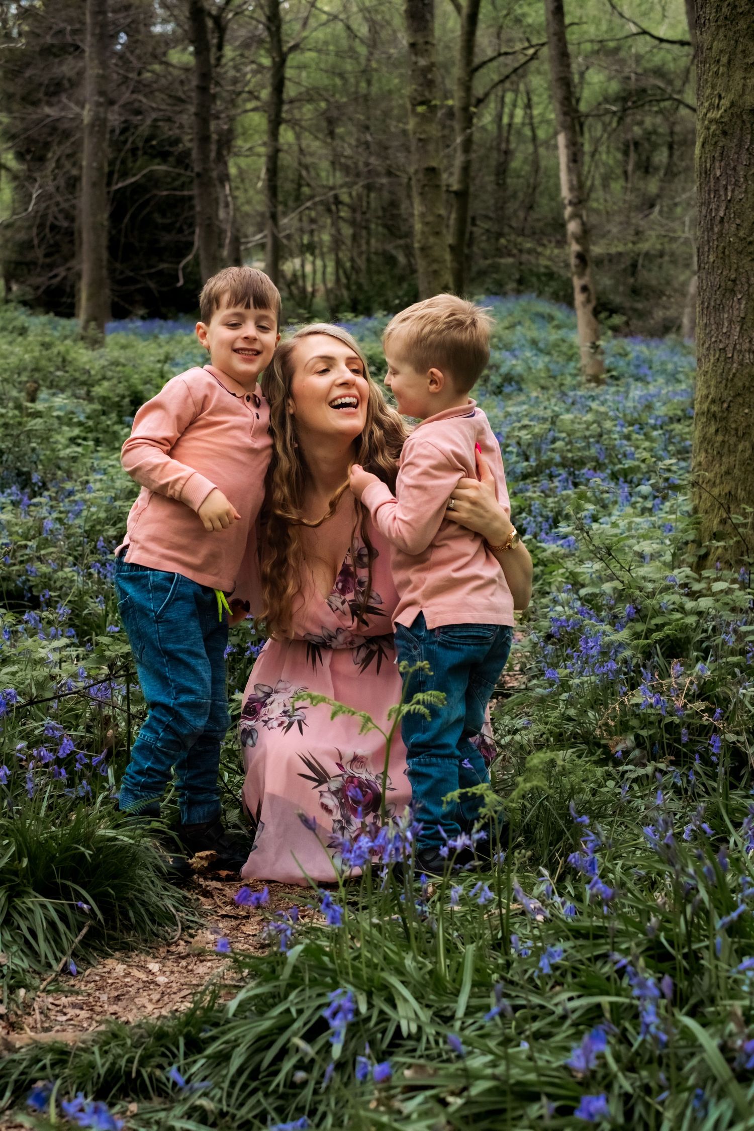 mum and toddlers laughing together in a bluebell family photo session near Horsham