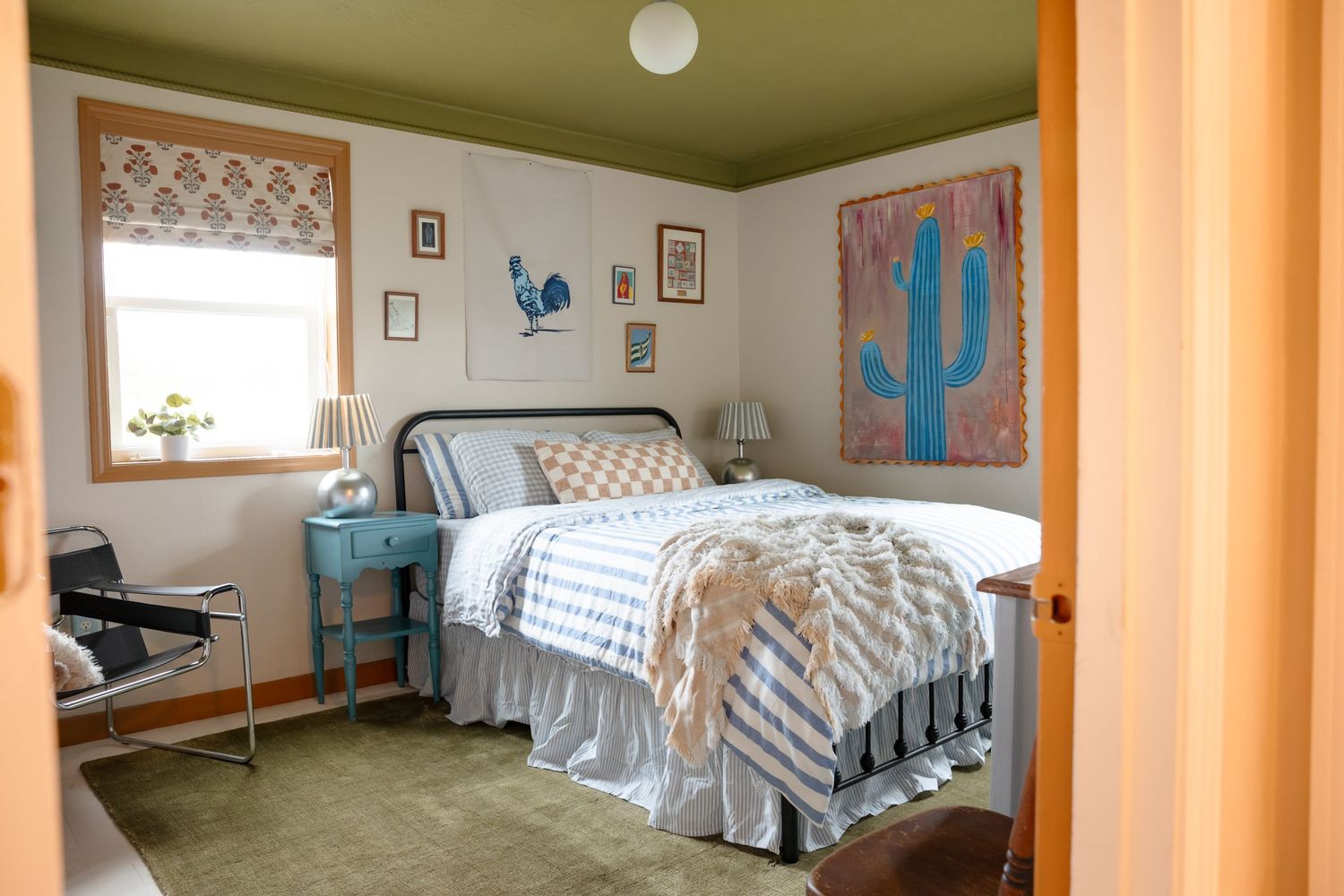 Bright bedroom with southwestern decor featuring a cactus print and striped bedding.
