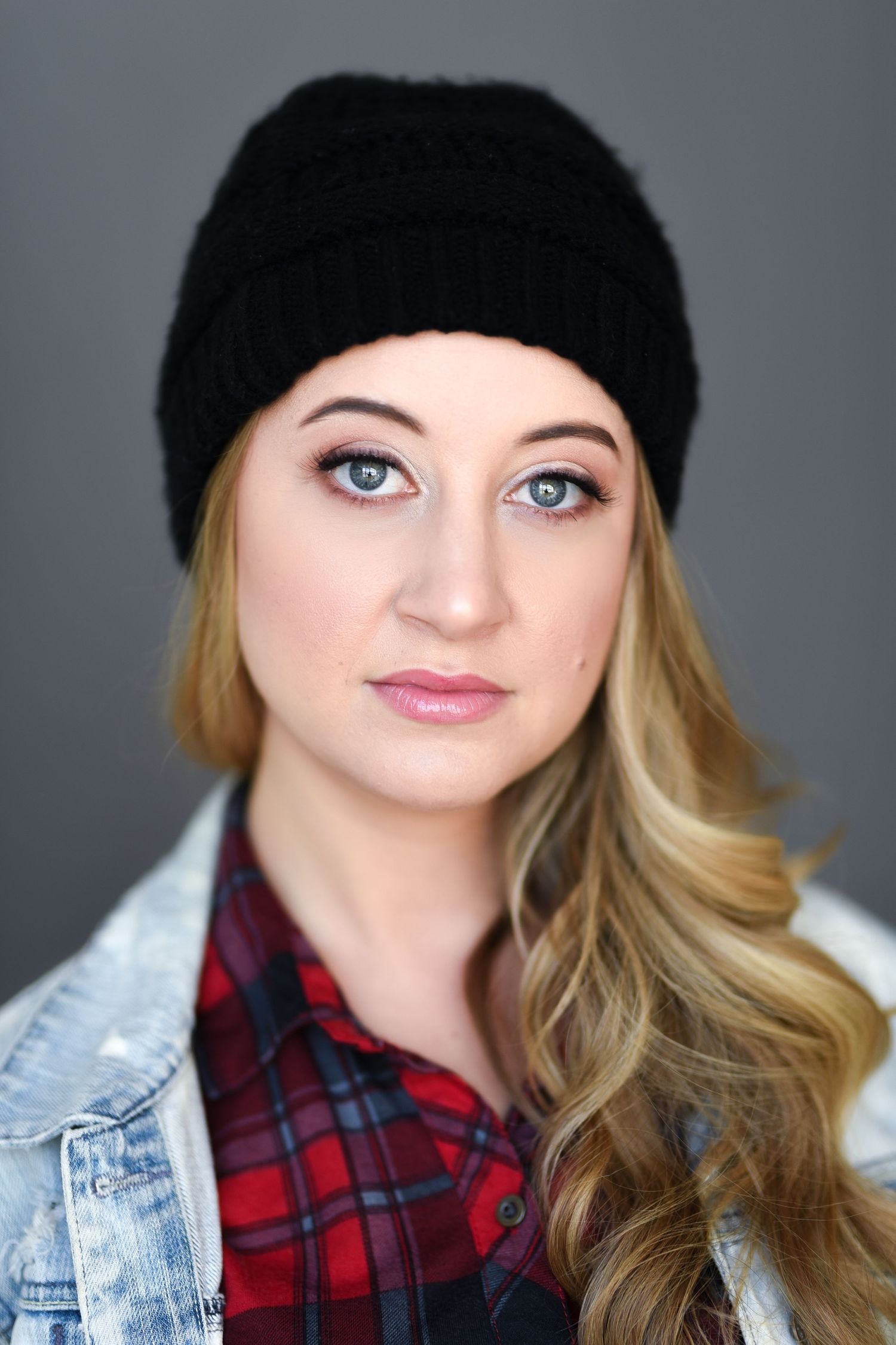 Winter fashion portrait with black beanie, plaid shirt and denim jacket.