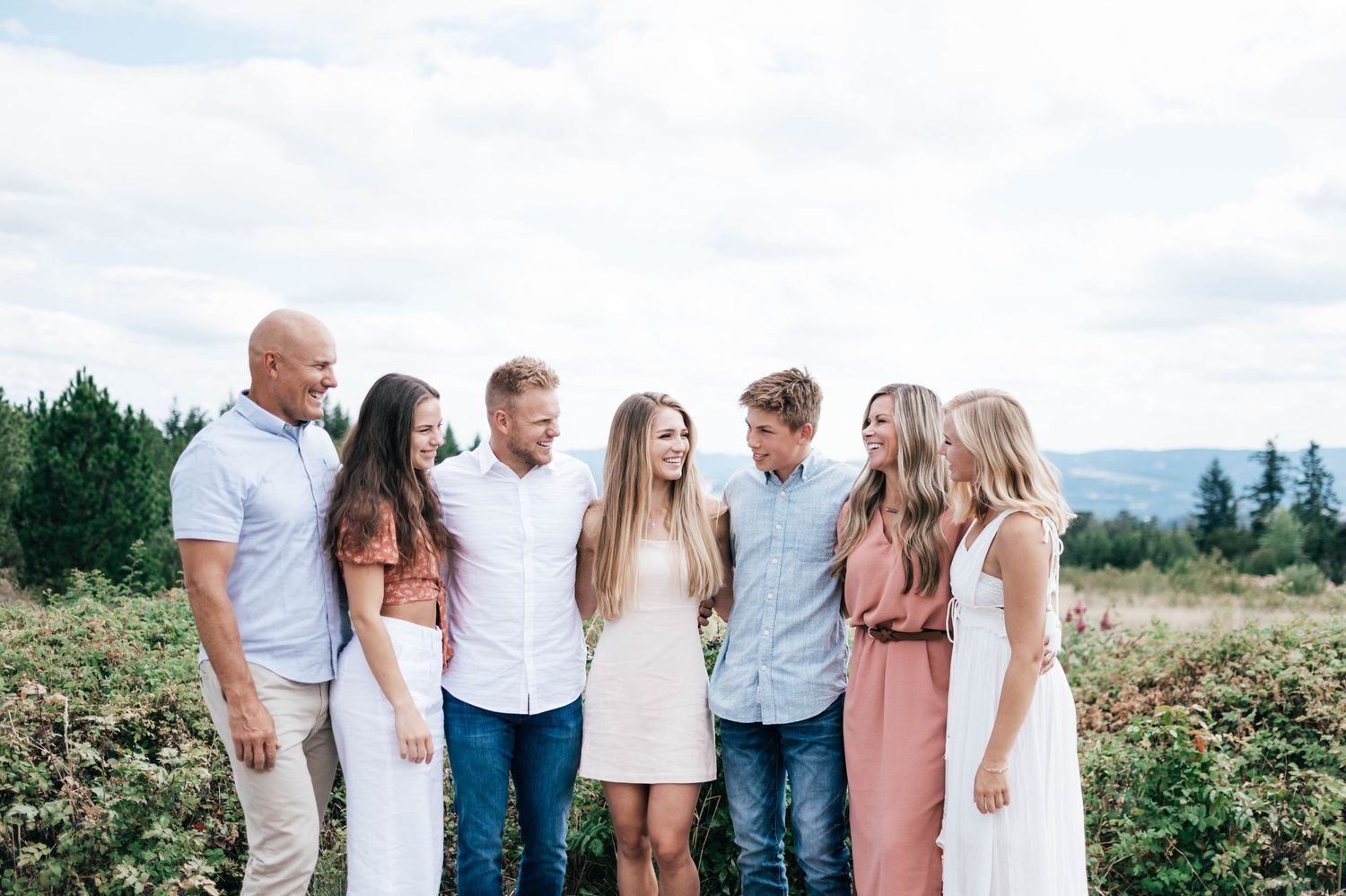 Group portrait of people in coordinated white and pink outfits against mountain backdrop.