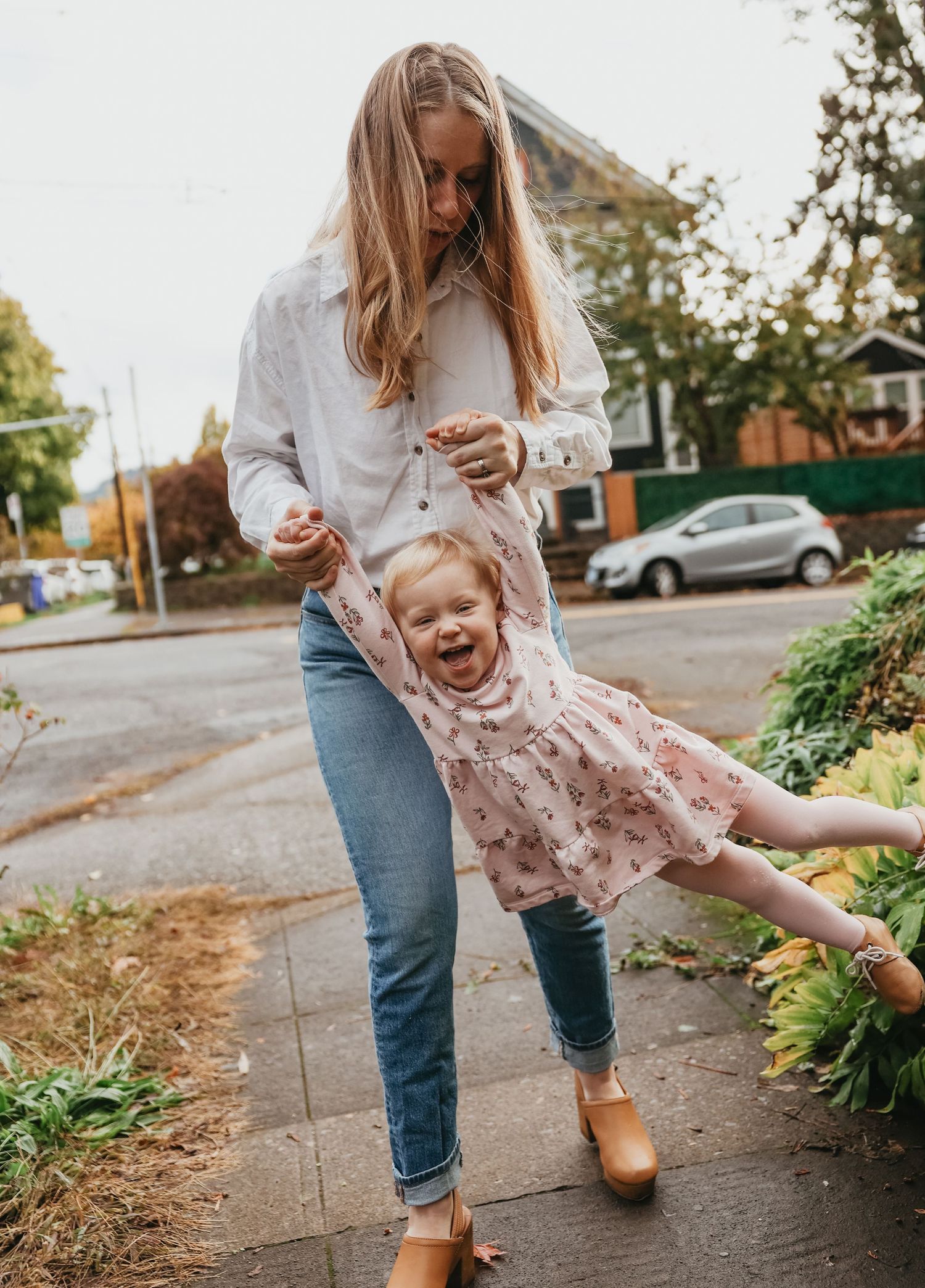 Playful moment captured on a residential sidewalk with joyful swinging motion.