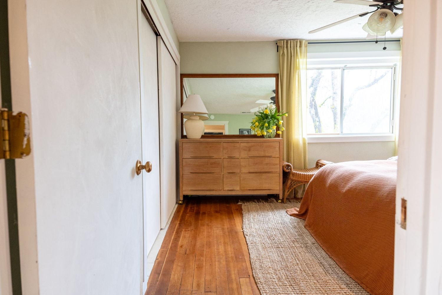 Modern bedroom with wooden floors, beige runner rug, and mid-century dresser.