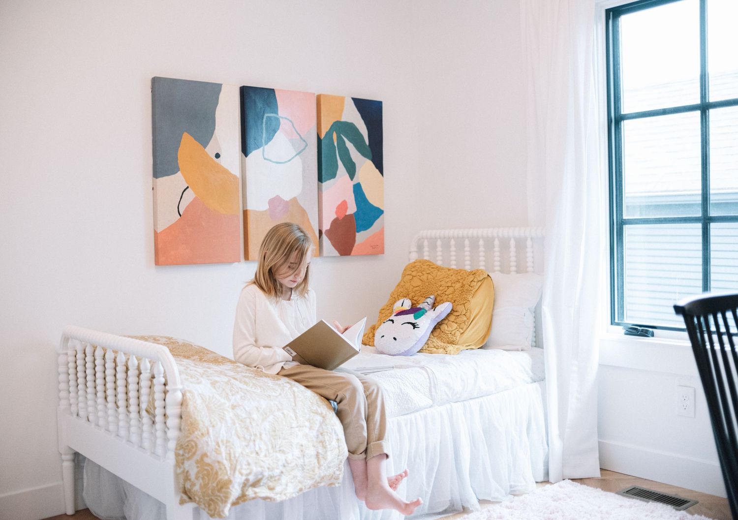 Modern bedroom featuring white bedding and large abstract wall art in blue and peach tones.