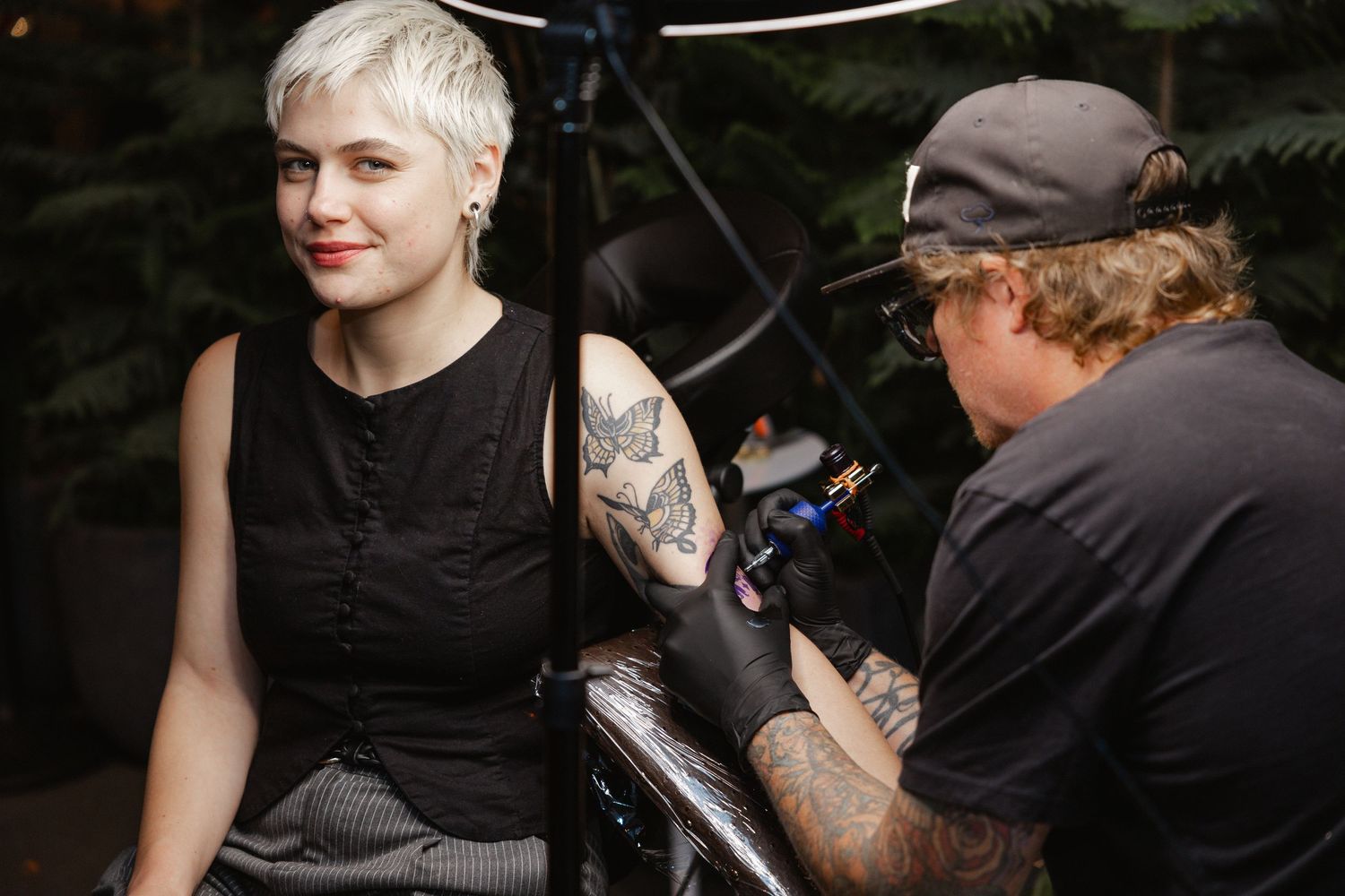 Artist applies a tattoo in a professional studio setting while wearing protective gloves and equipment.