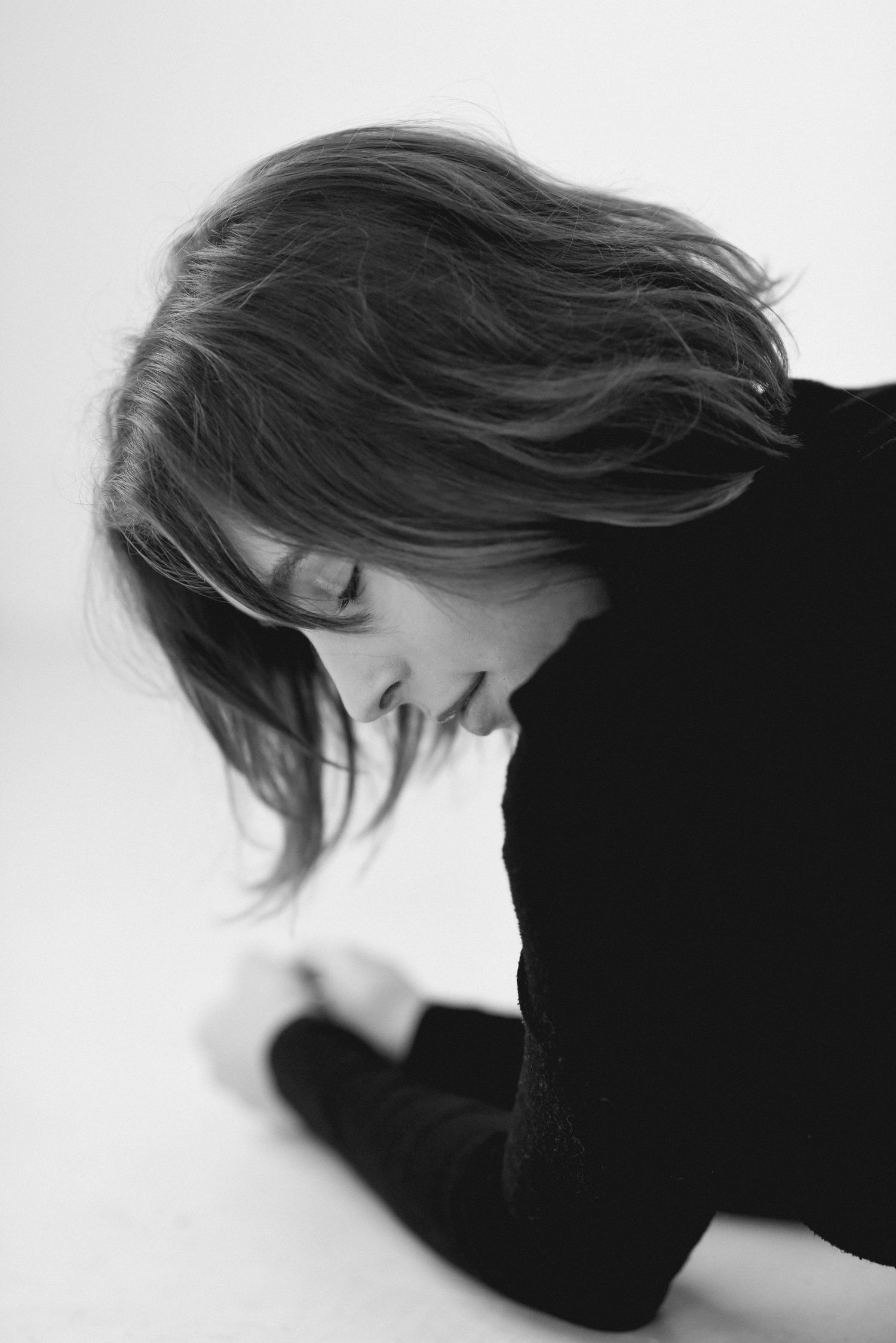 Black and white artistic portrait showing flowing hair movement against white background.