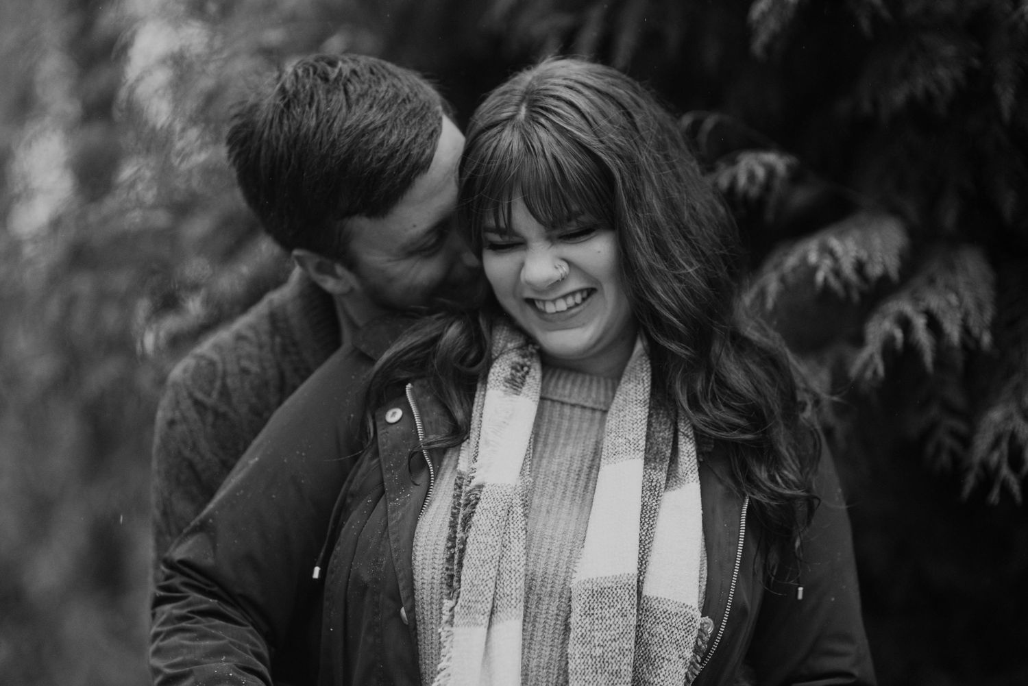 Black and white portrait of a couple sharing an intimate moment outdoors.