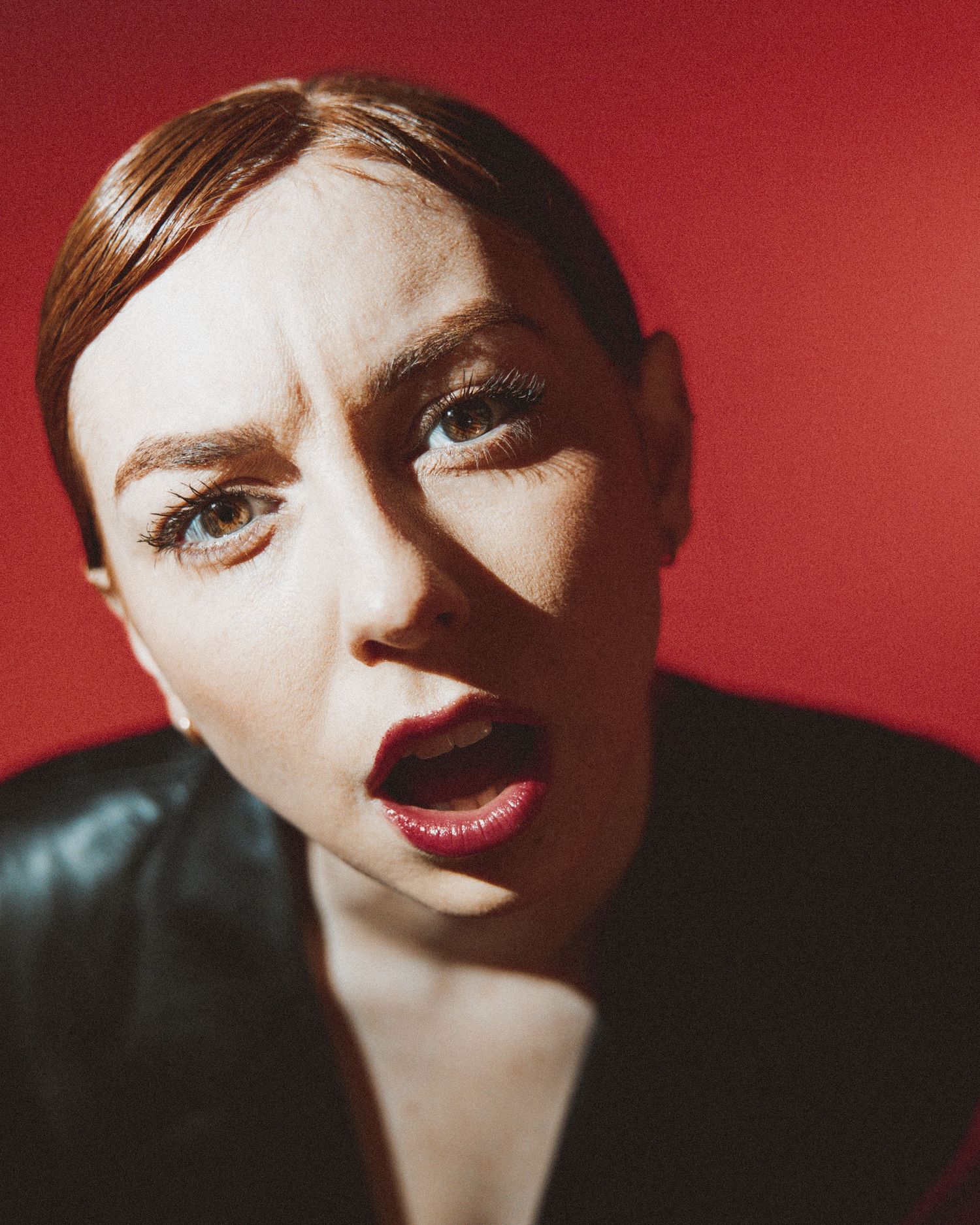 Artistic portrait series in red lighting showing dramatic shadows and bold lipstick in varying close-up angles.