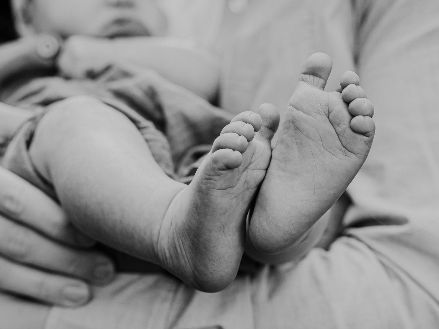 Close-up black and white photograph of tiny baby feet.