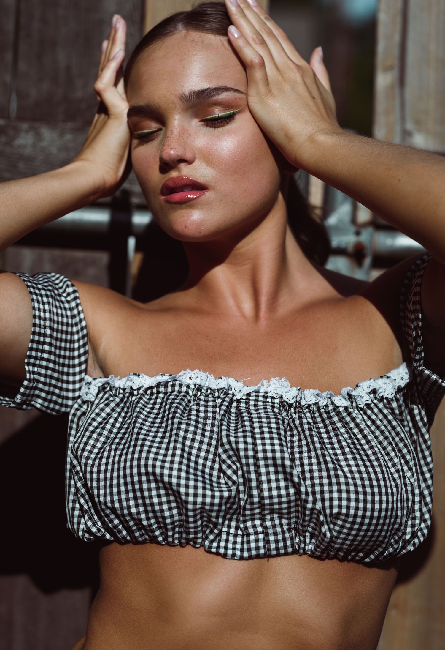 Close-up fashion photo featuring gingham off-shoulder top and sun-kissed makeup.