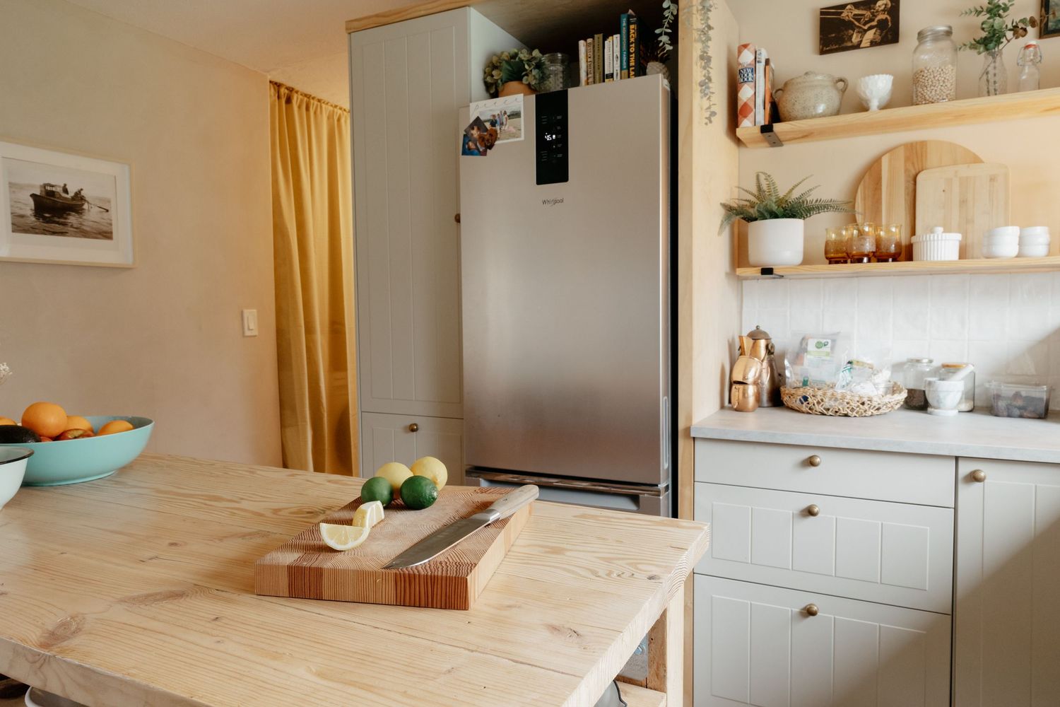 Minimalist kitchen interior with wooden island and open shelving displaying kitchenware.
