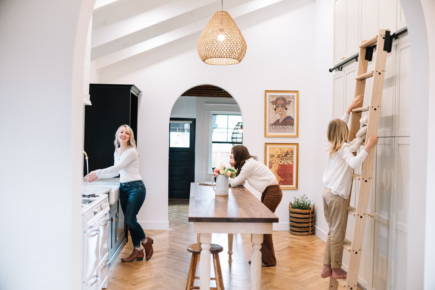 Modern white kitchen with arched doorways and wooden ladder against the wall.