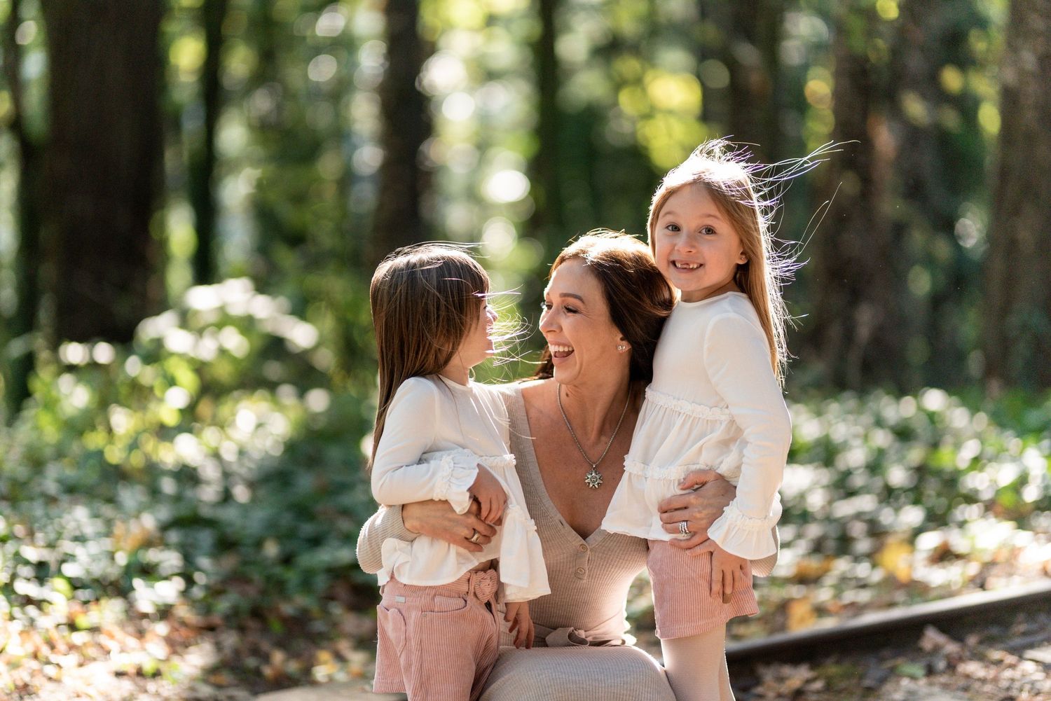 Sweet outdoor family moment captured in sunlit forest setting.