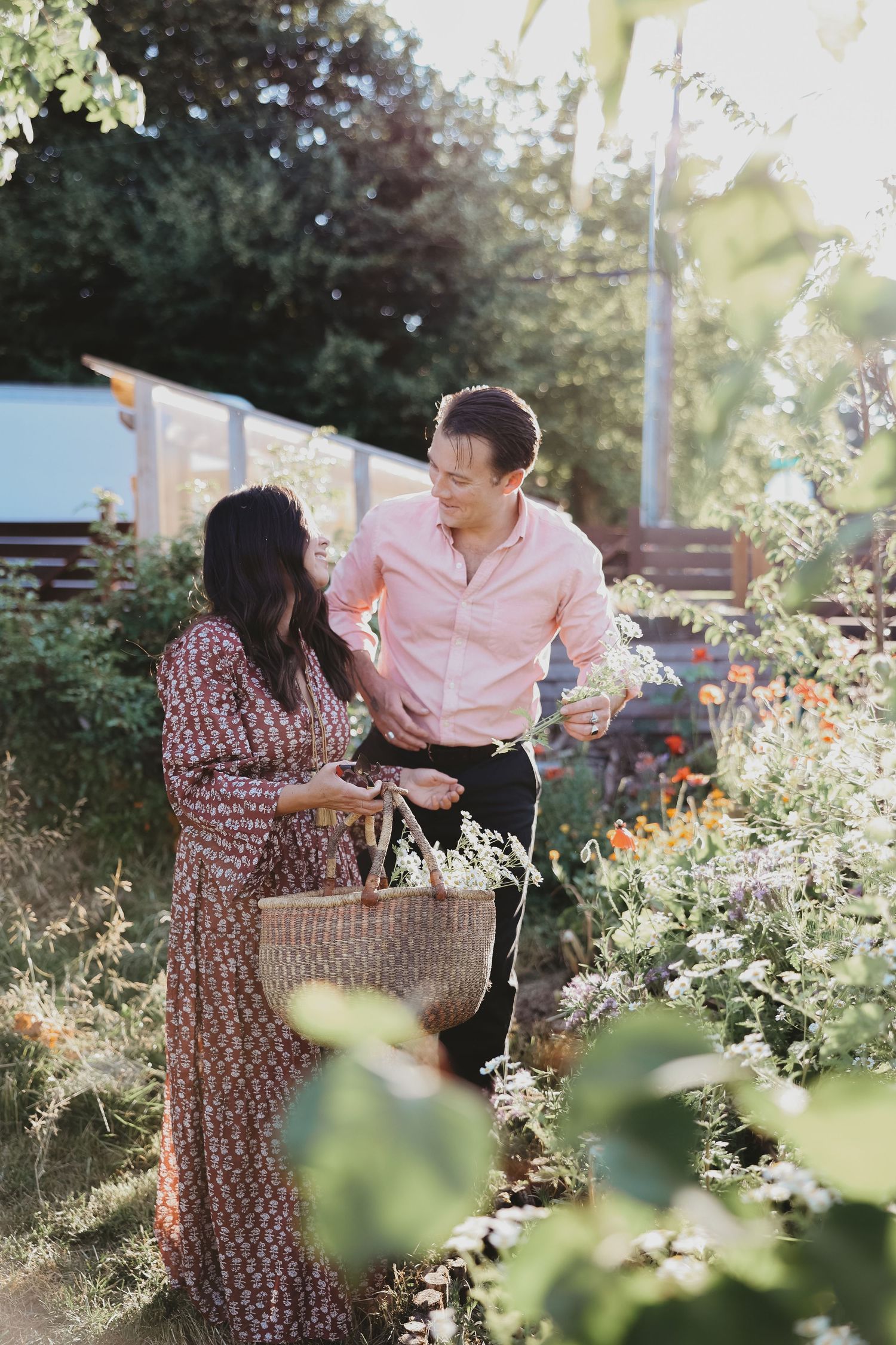 A romantic couple sharing a sweet moment in a sunlit garden with blooming flowers.