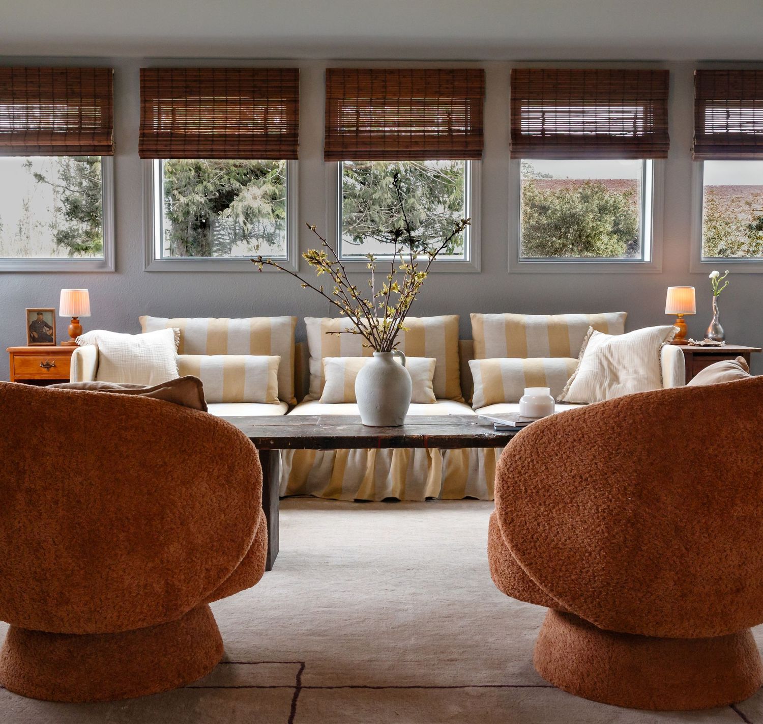 Mid-century modern living room with retro swivel chairs and large windows with bamboo shades.