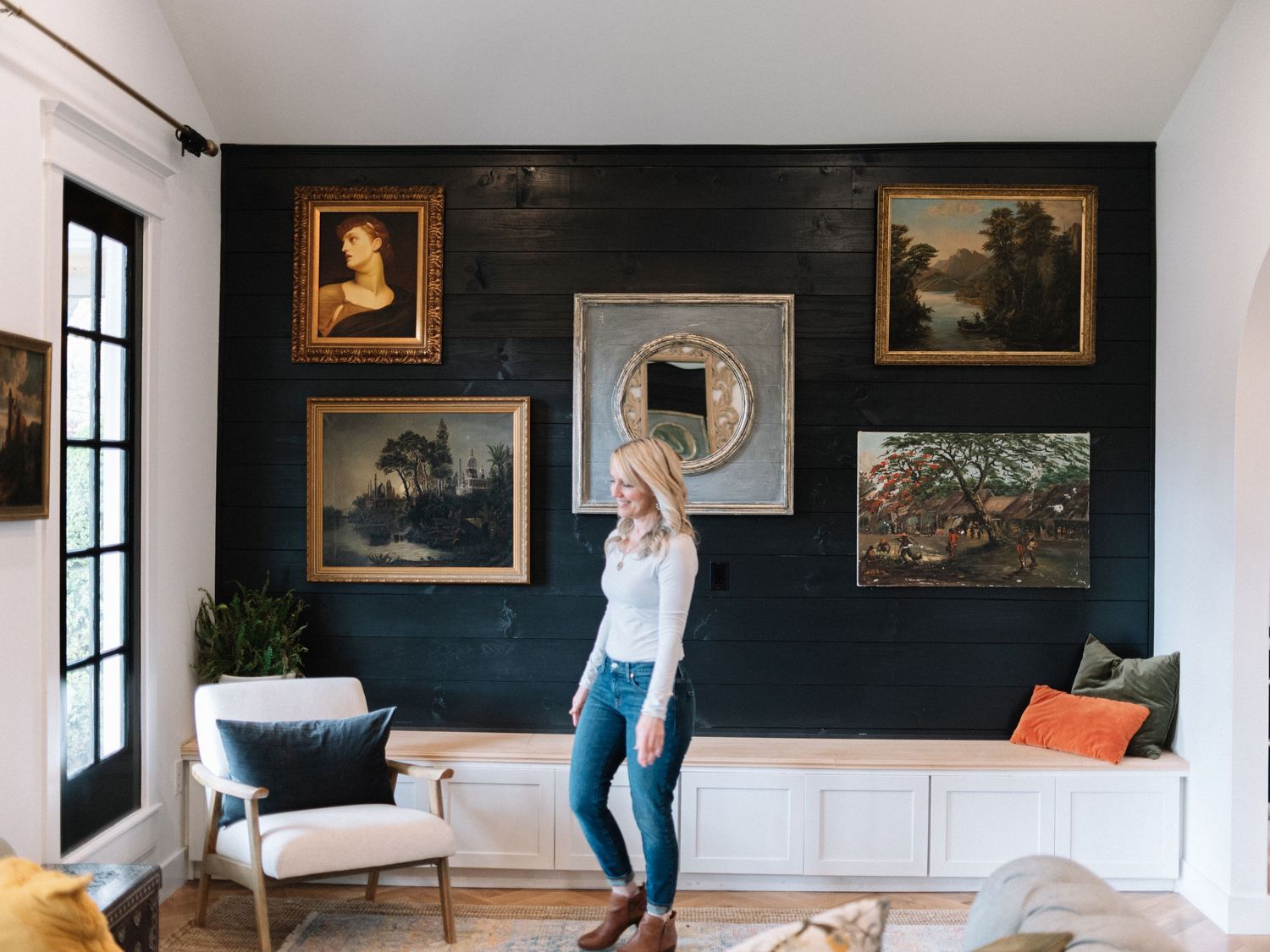 Living room featuring a dramatic black accent wall with vintage artwork and built-in bench seating.