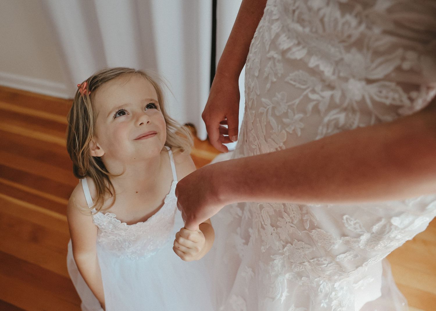 A small child in white looking up adoringly at someone in a wedding dress.