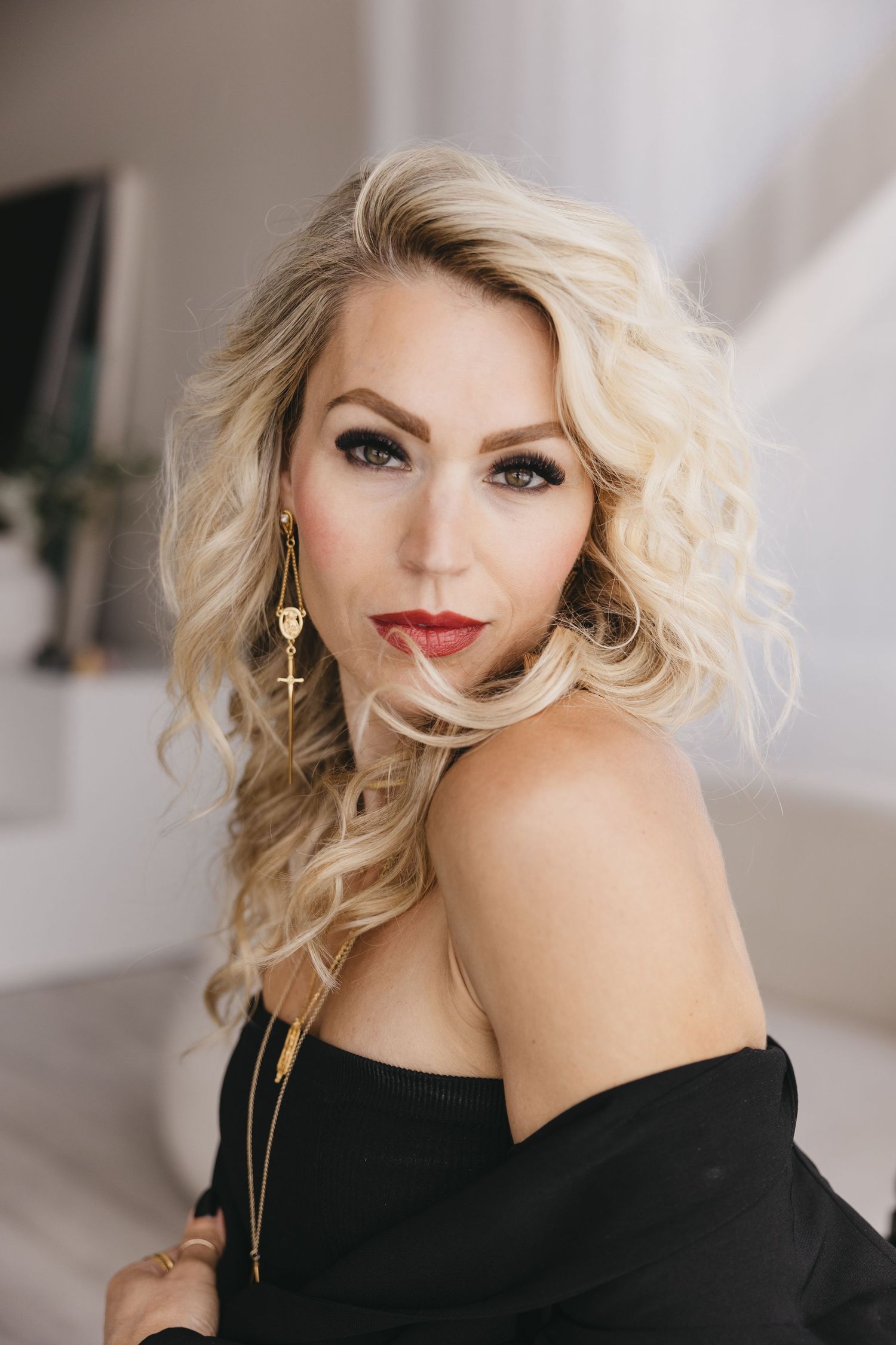 Close-up portraits with dramatic lighting showing wavy blonde hair, black top, and glamorous makeup styling.