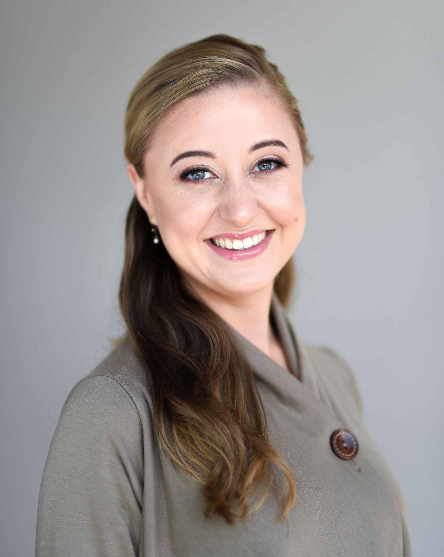 Professional portrait in a grey button-up jacket against a light backdrop.