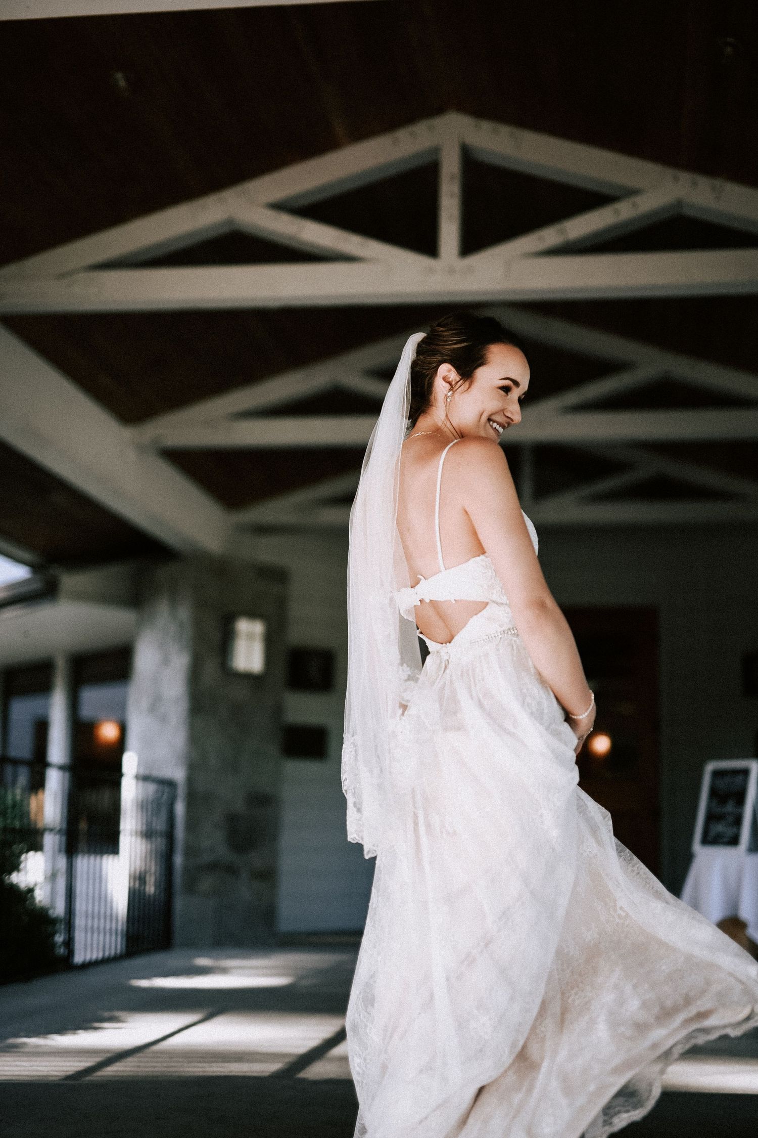 A bride twirls in her flowing white wedding dress showing off the open back detail.