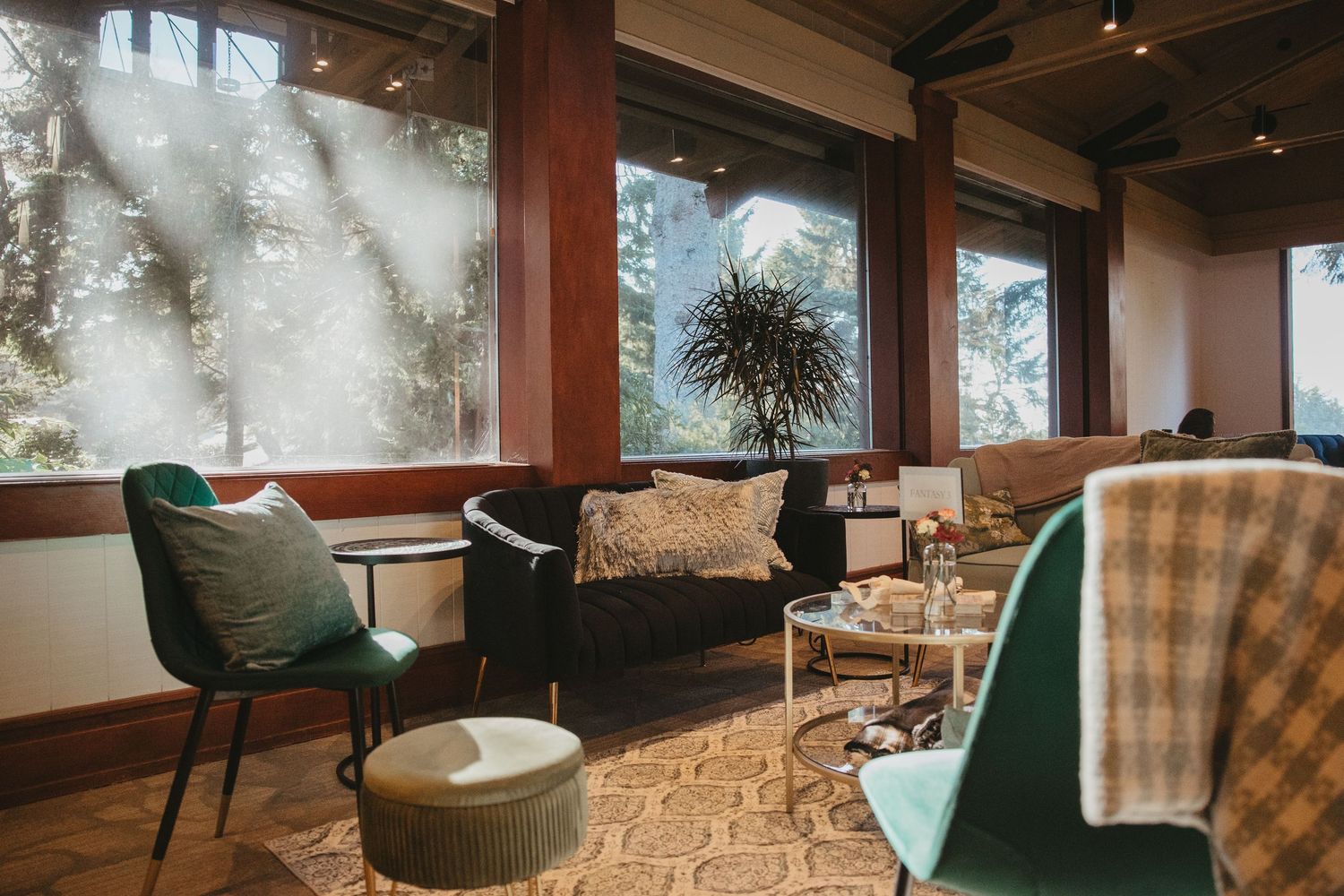 Modern office space features green accent chairs, plaid wallpaper, and large windows overlooking natural scenery.