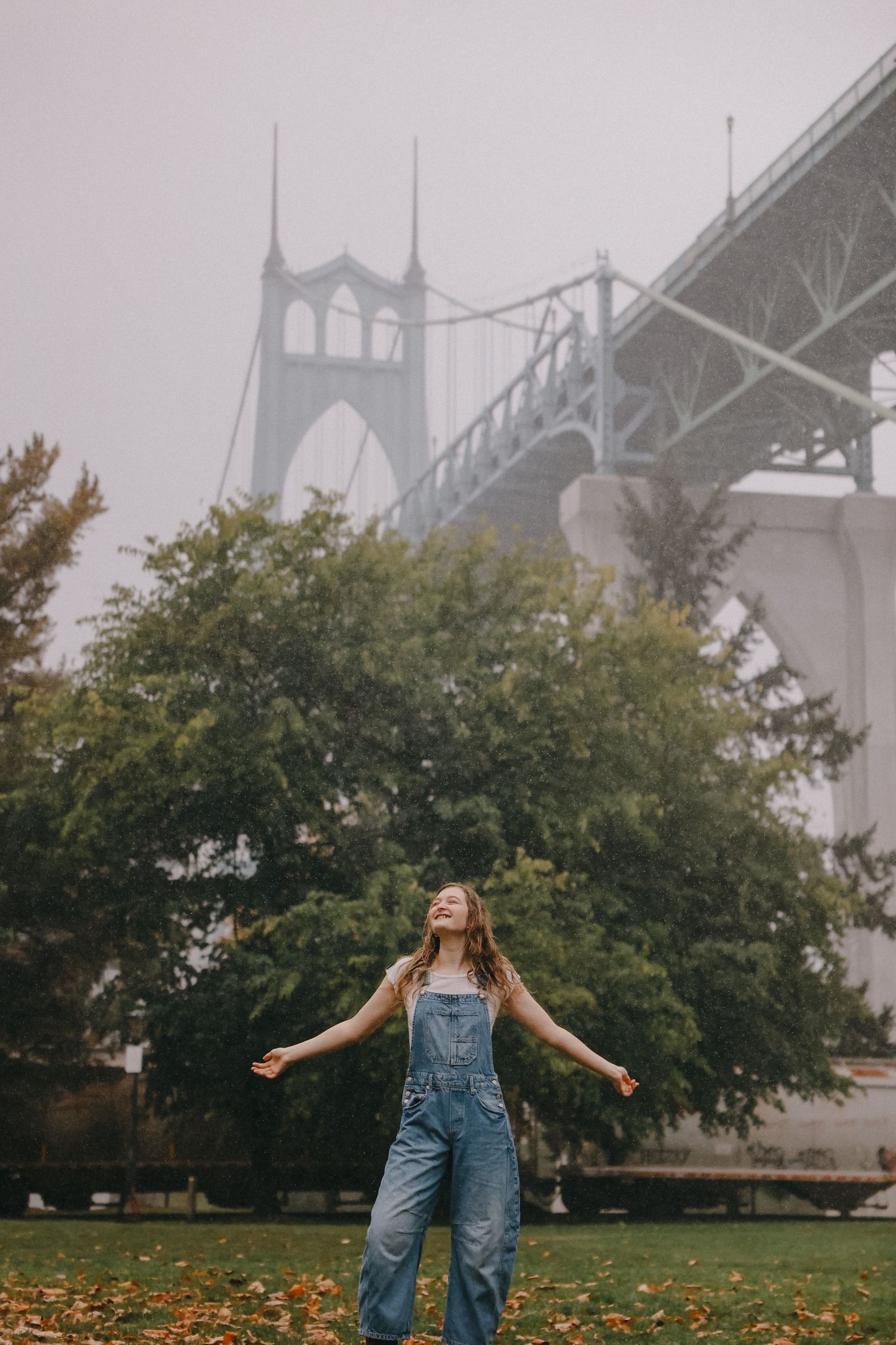 Joyful pose near St. Johns Bridge in Portland on foggy autumn day.
