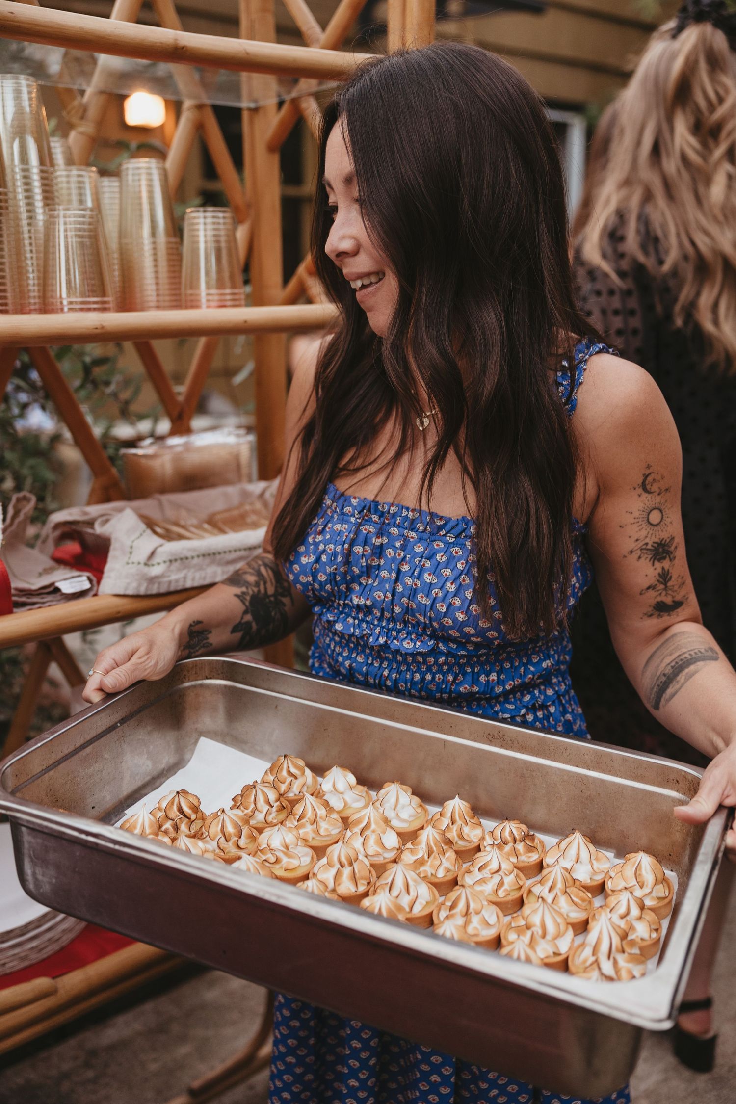 A tray of freshly piped meringue cookies being shown at a gathering with people in casual attire.