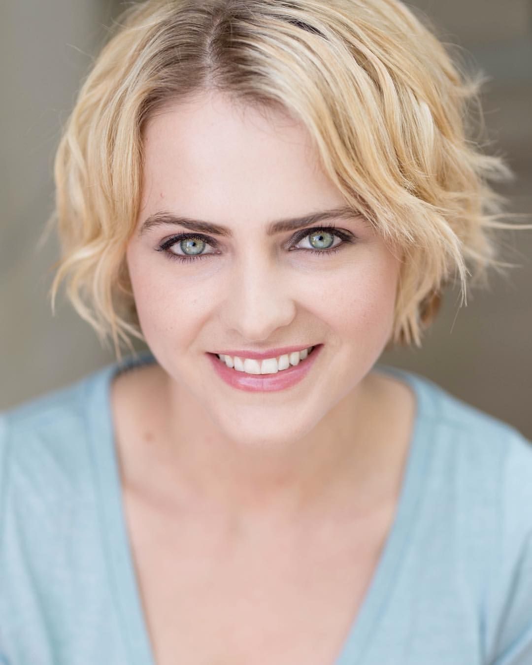 Professional headshot with short blonde hair and gentle smile.
