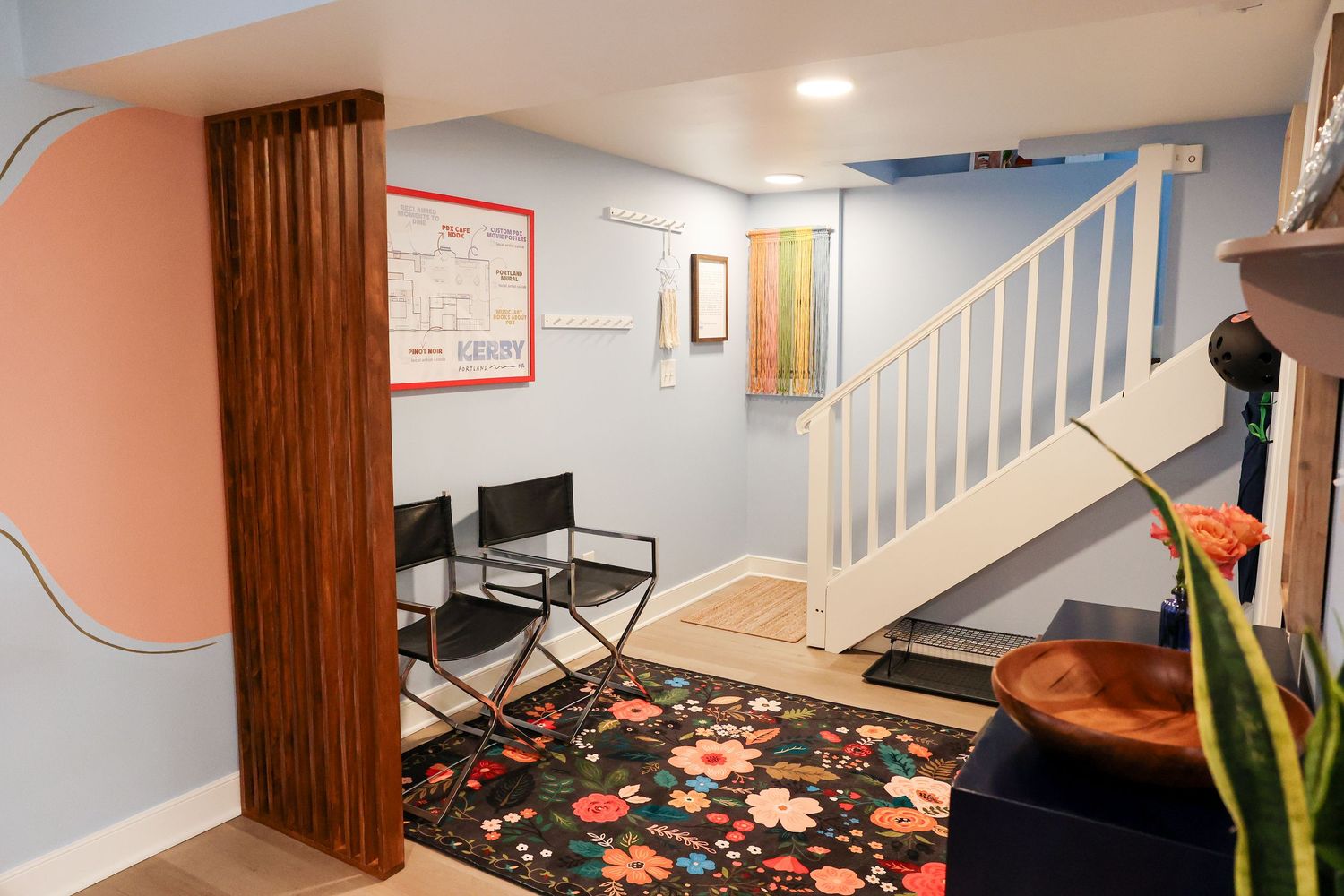 Cozy basement sitting area with floral rug, wooden accents, and white staircase.