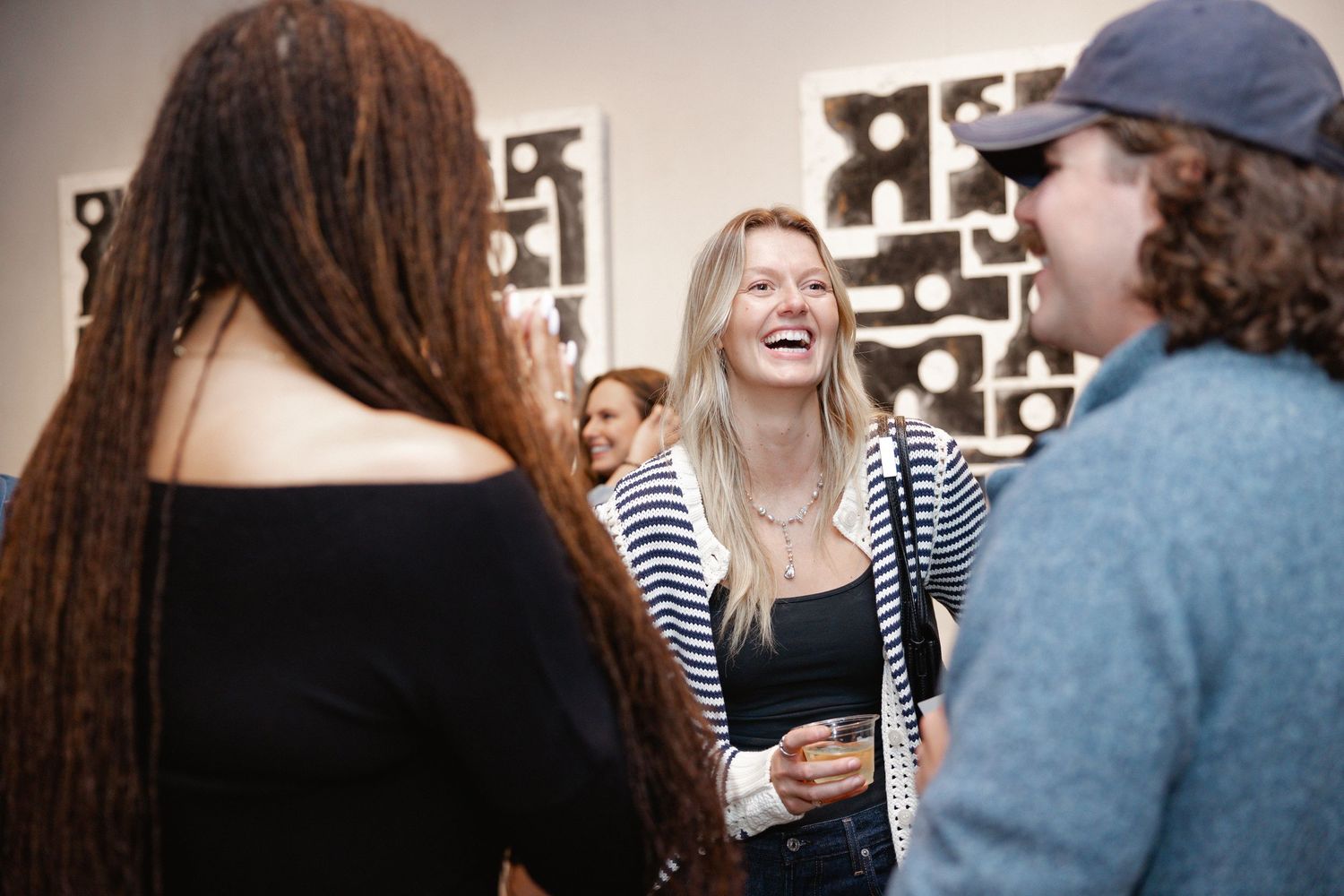 Group of people sharing laughter and conversation in a casual social gathering setting.