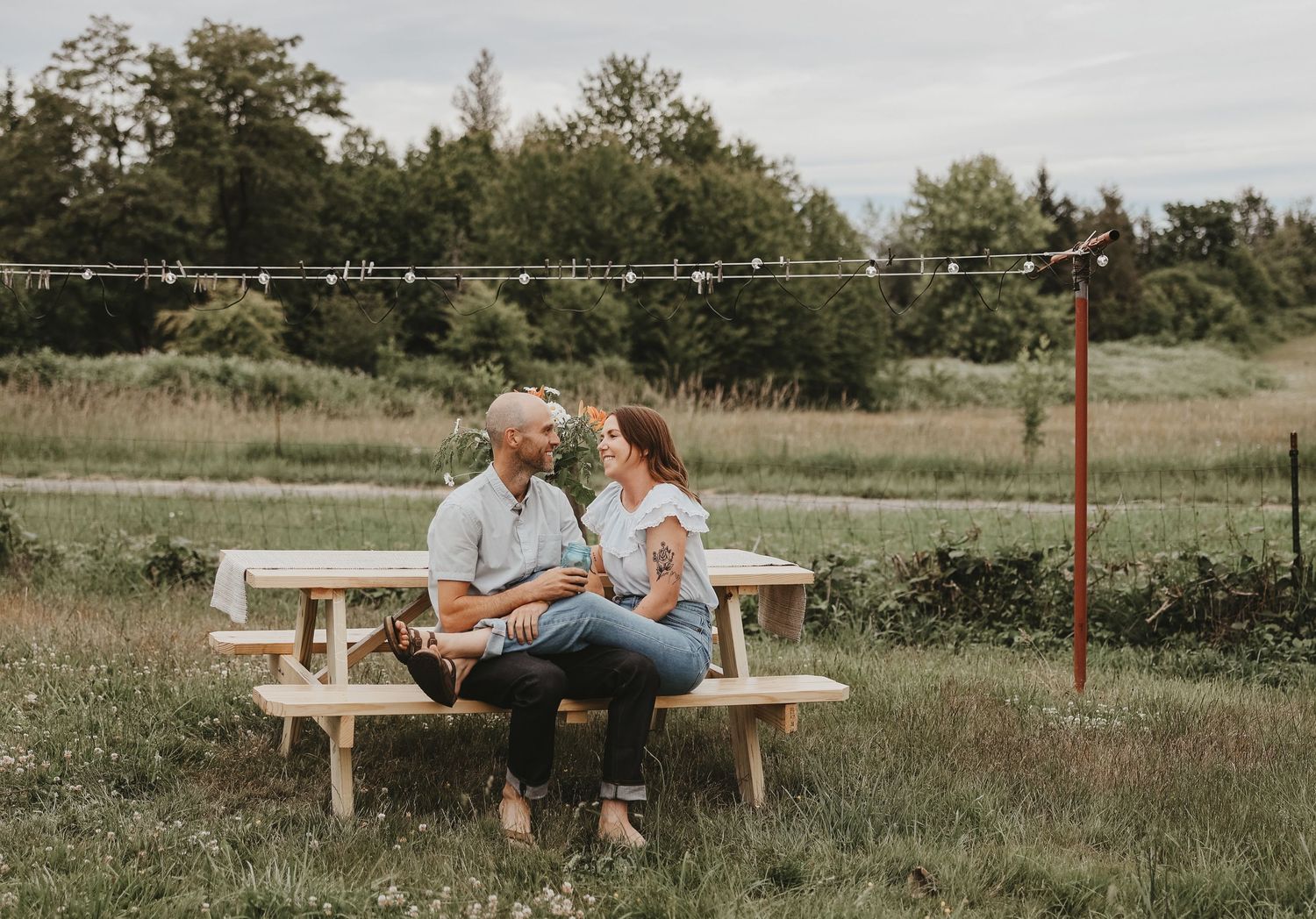 A couple shares an intimate moment on a wooden bench in a peaceful countryside setting.