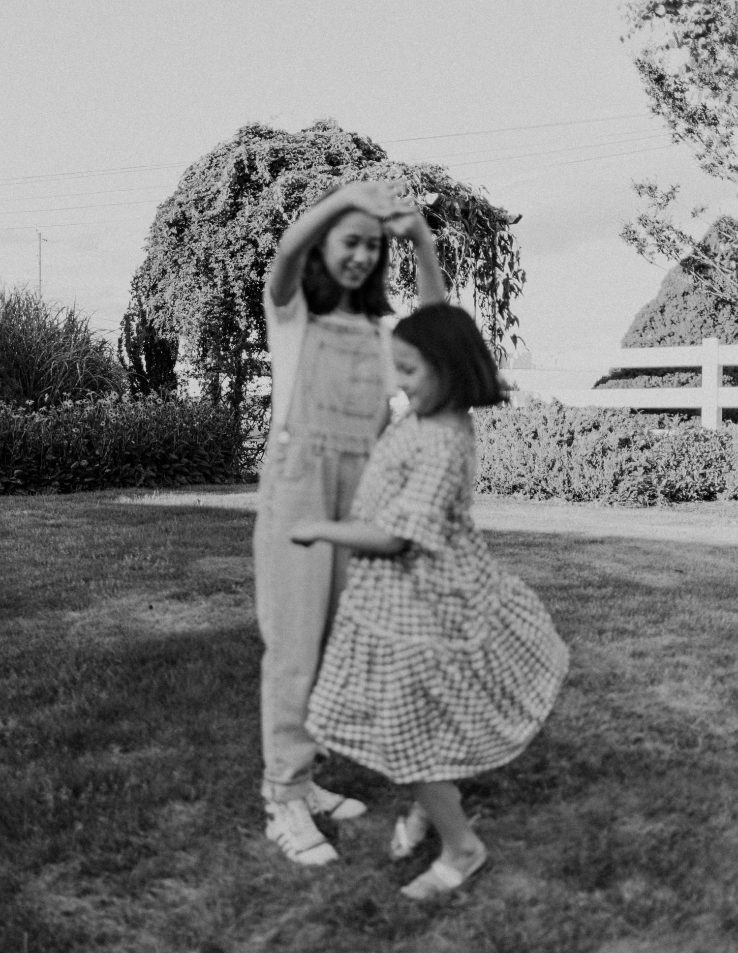 A vintage black and white photo of two people dancing together in a garden.