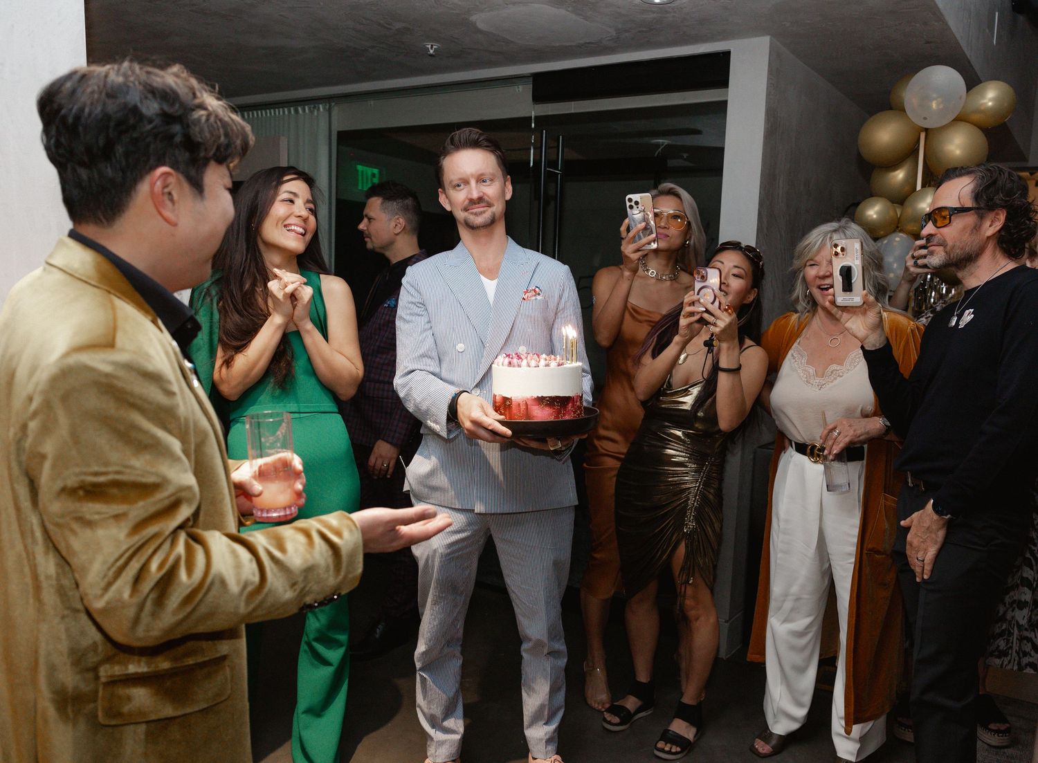A group of people mingle and socialize at an indoor gathering or party event.