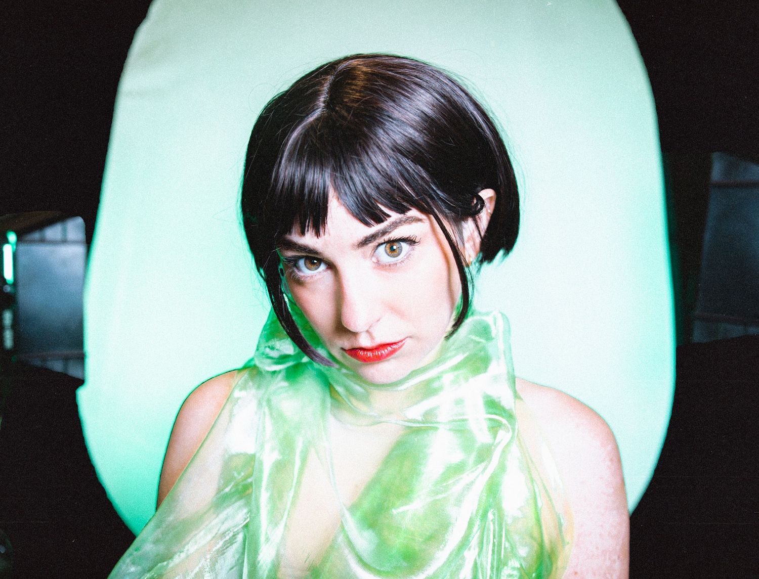 Four sequential photos show someone posing with a green sheer fabric against a dark background.