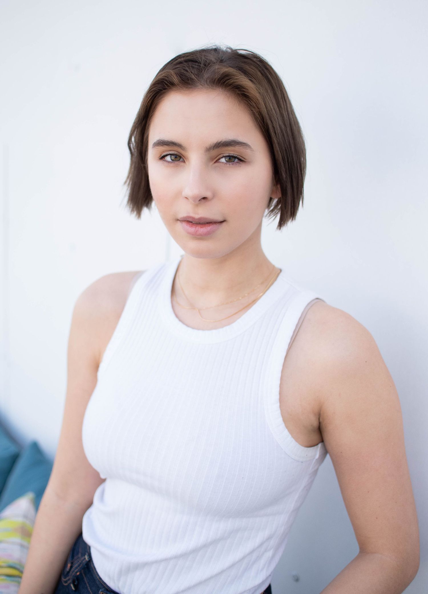 Casual portrait wearing a sleeveless white top against a white background.