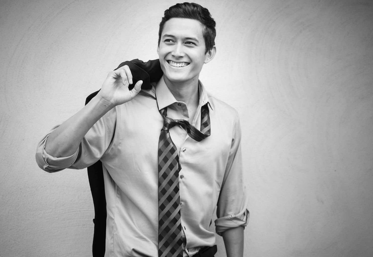 Professional black and white portrait of person in business attire with tie and phone.