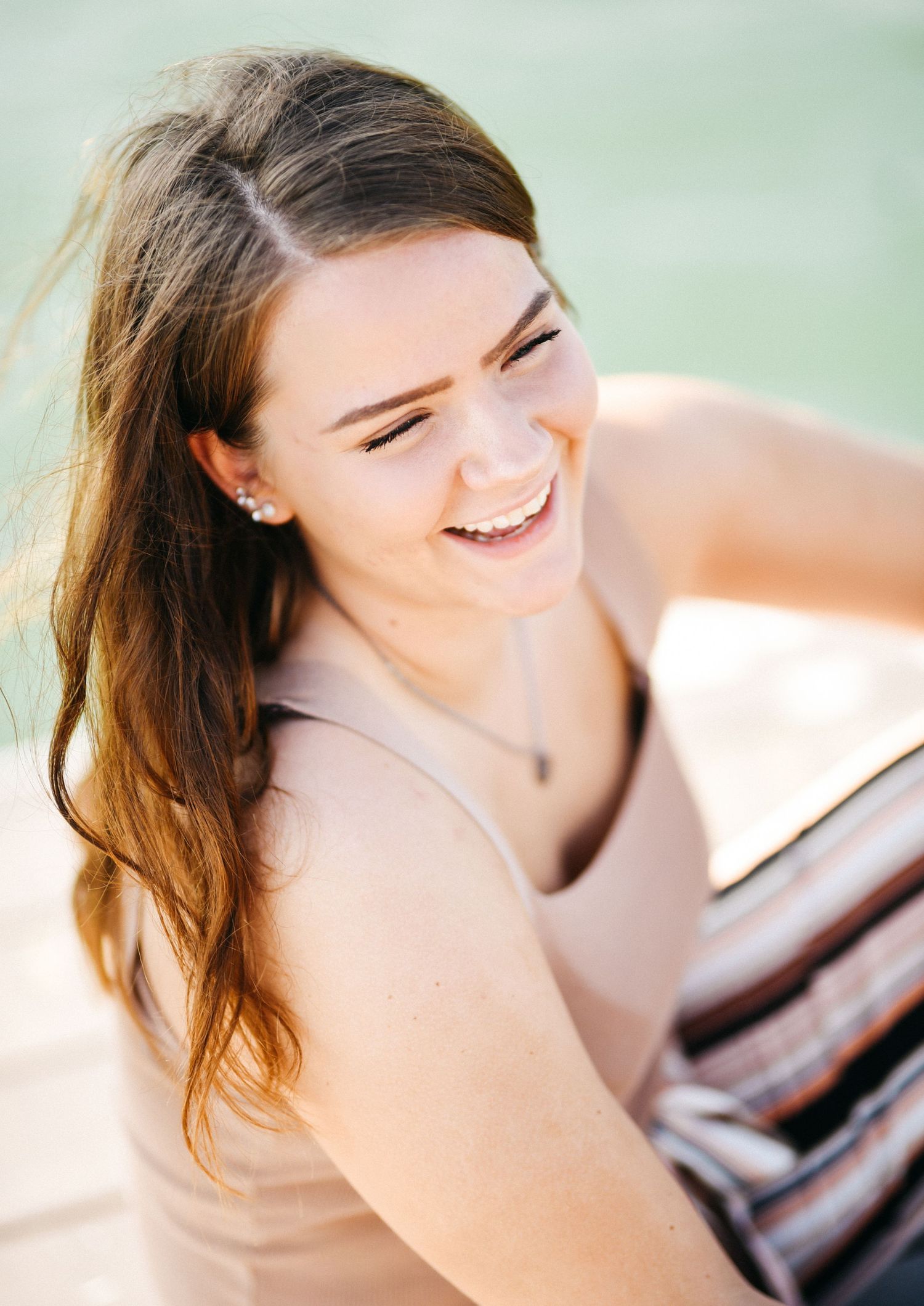 Candid lifestyle portrait of laughing woman in beige outfit with natural lighting.