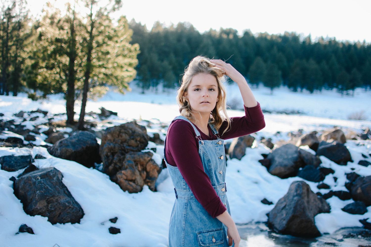 Carefree winter portrait among snow covered rocks and evergreen trees.
