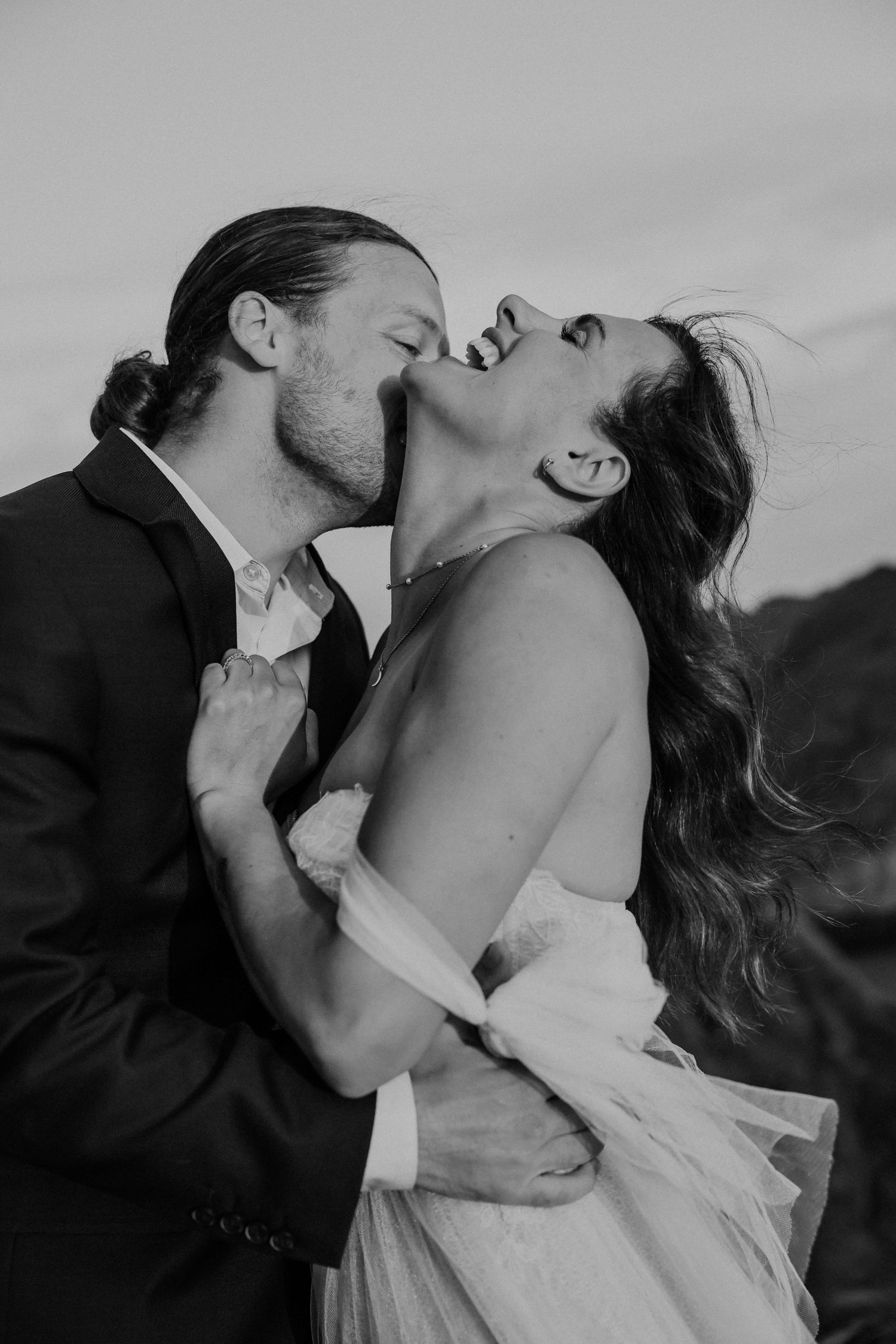 A passionate black and white portrait of a couple in wedding attire sharing an intimate moment.