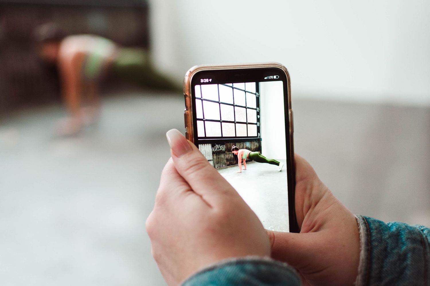 Hands holding smartphone capturing workout photo in minimalist white space.