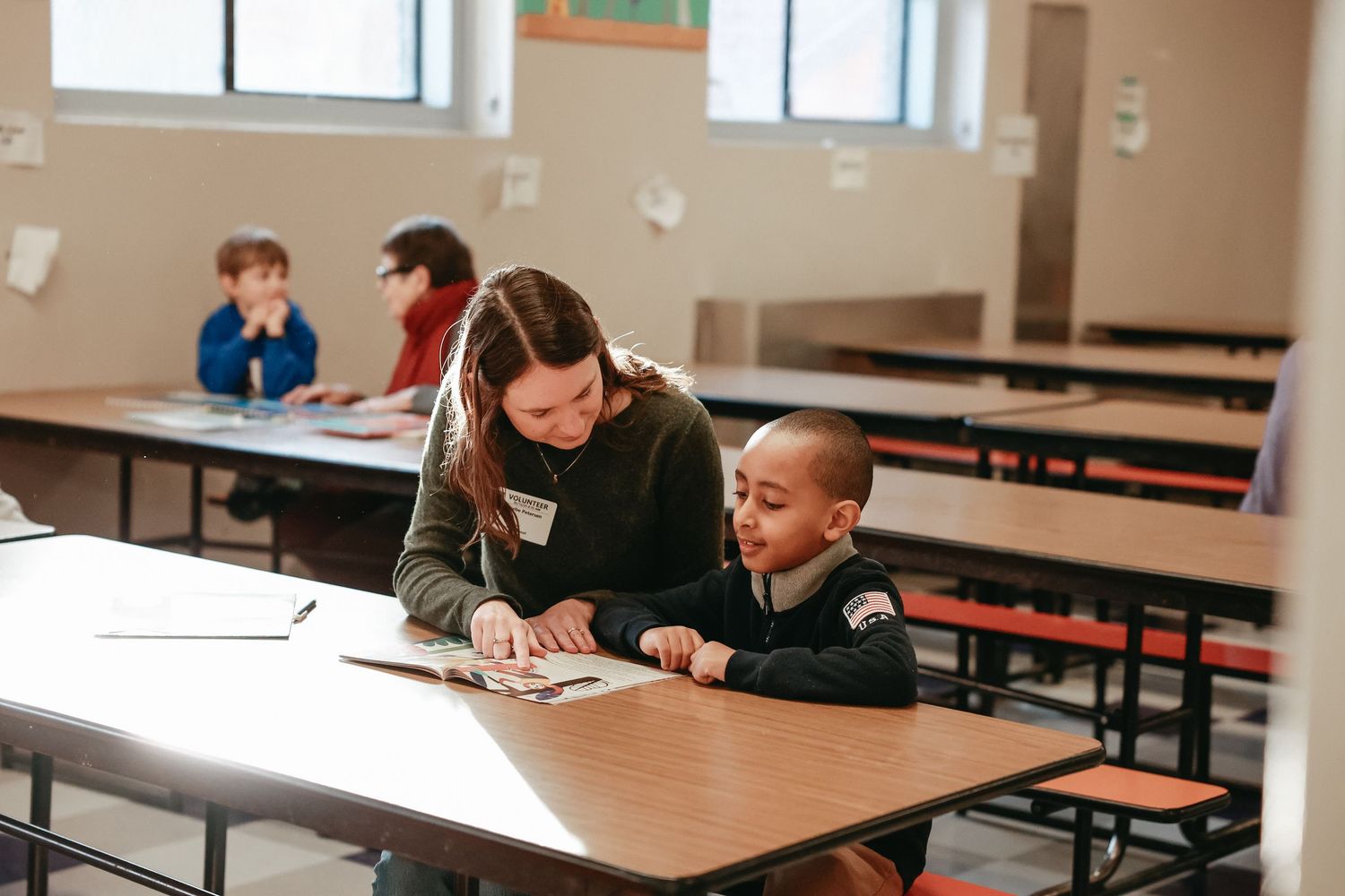 Students work together at wooden tables in a classroom setting during a collaborative learning session.