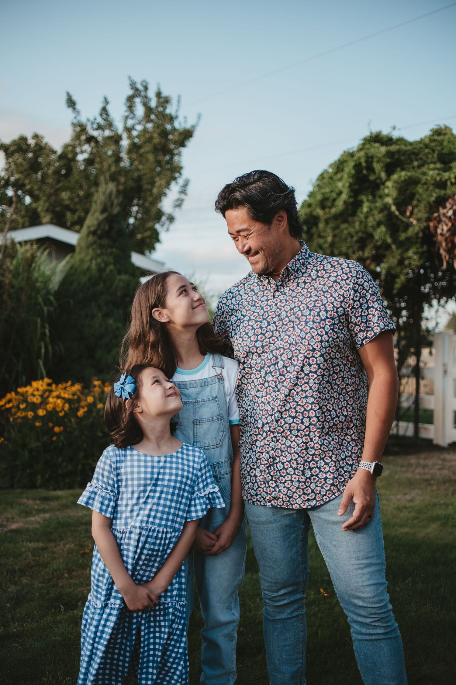 Family members share a tender moment together outdoors wearing coordinated blue outfits in a natural setting.