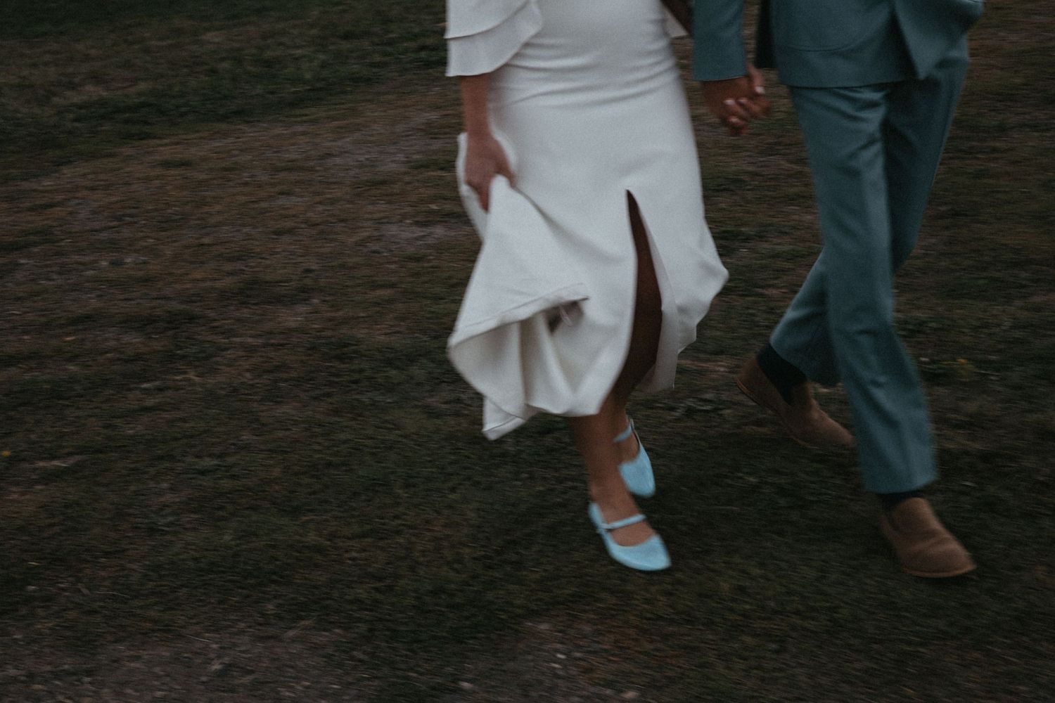 Close-up view of a bride and groom's feet walking together, with the bride wearing comfortable sneakers.